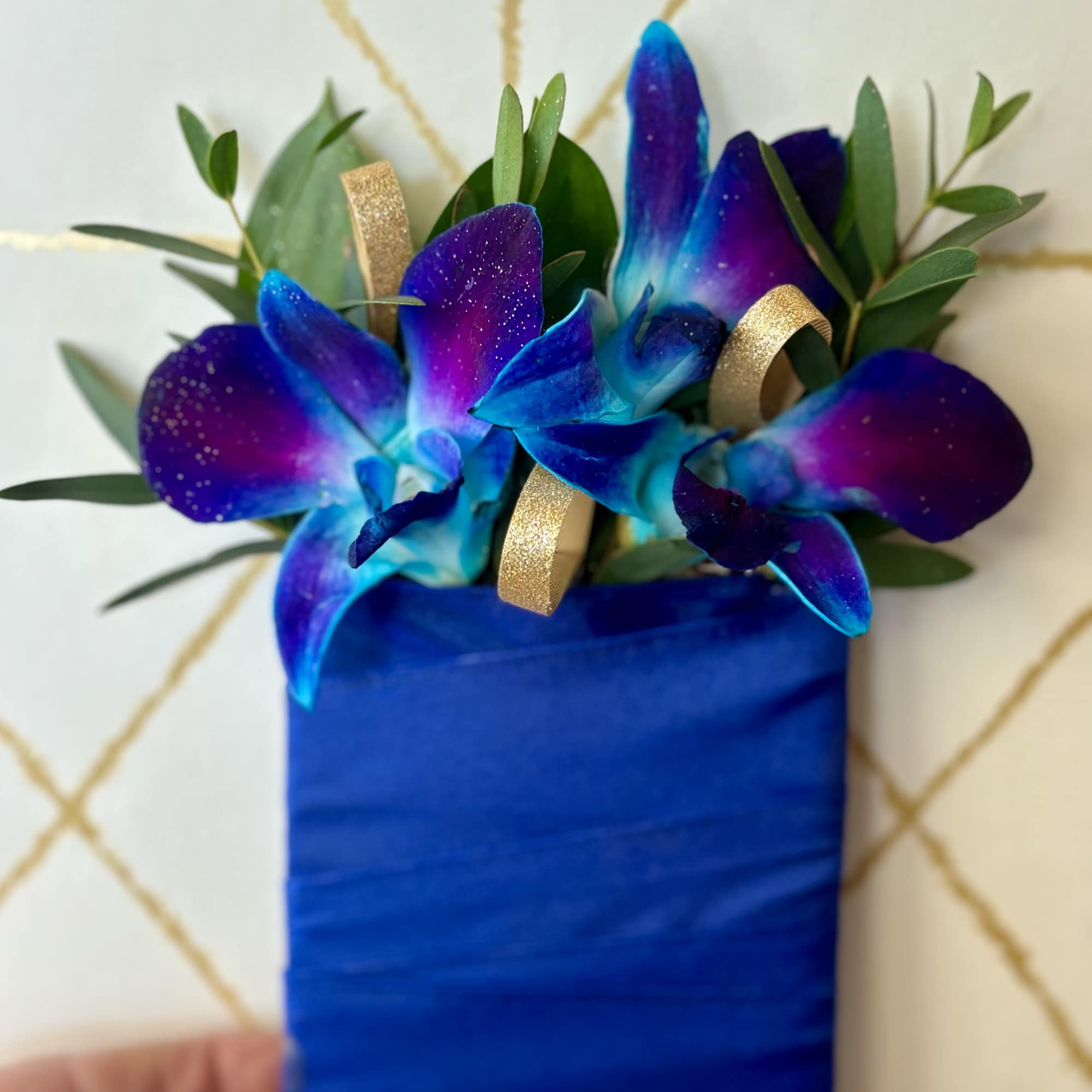 Blue orchid corsage with gold ribbon on a wrapped base