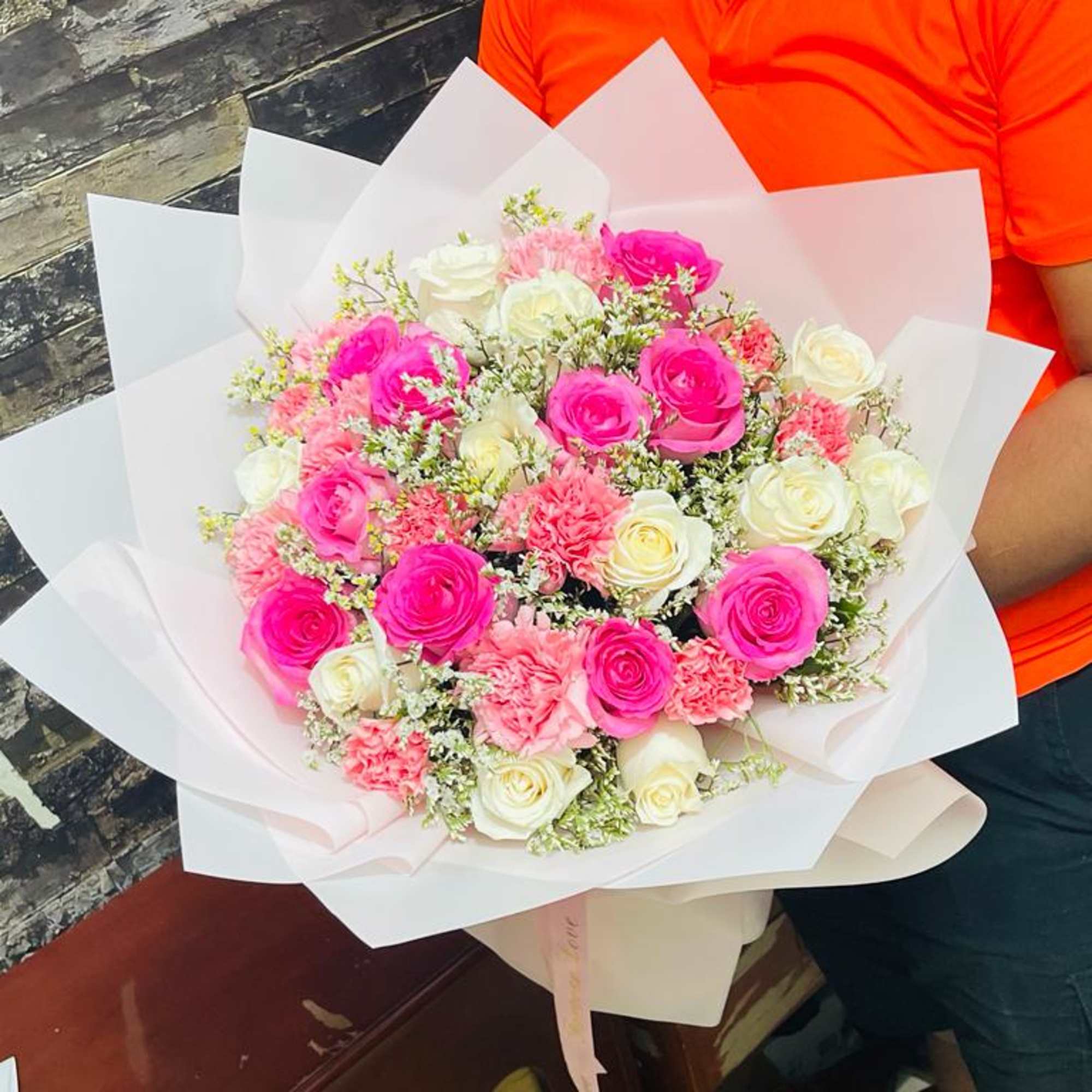 Bouquet of pink and white roses wrapped in white paper