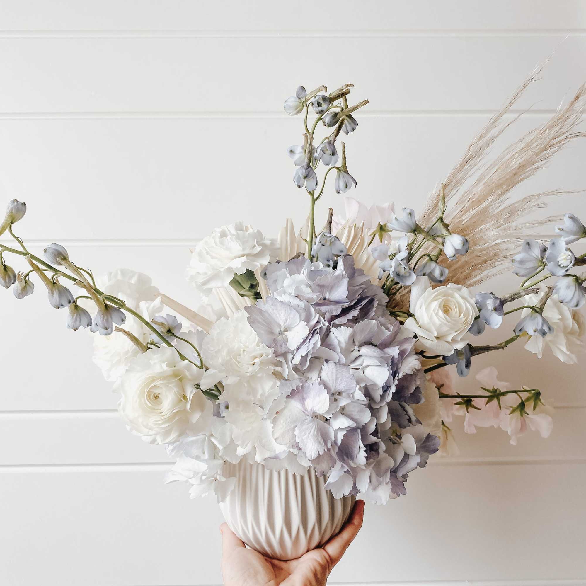 White and pale lavender floral arrangement in a ribbed vase