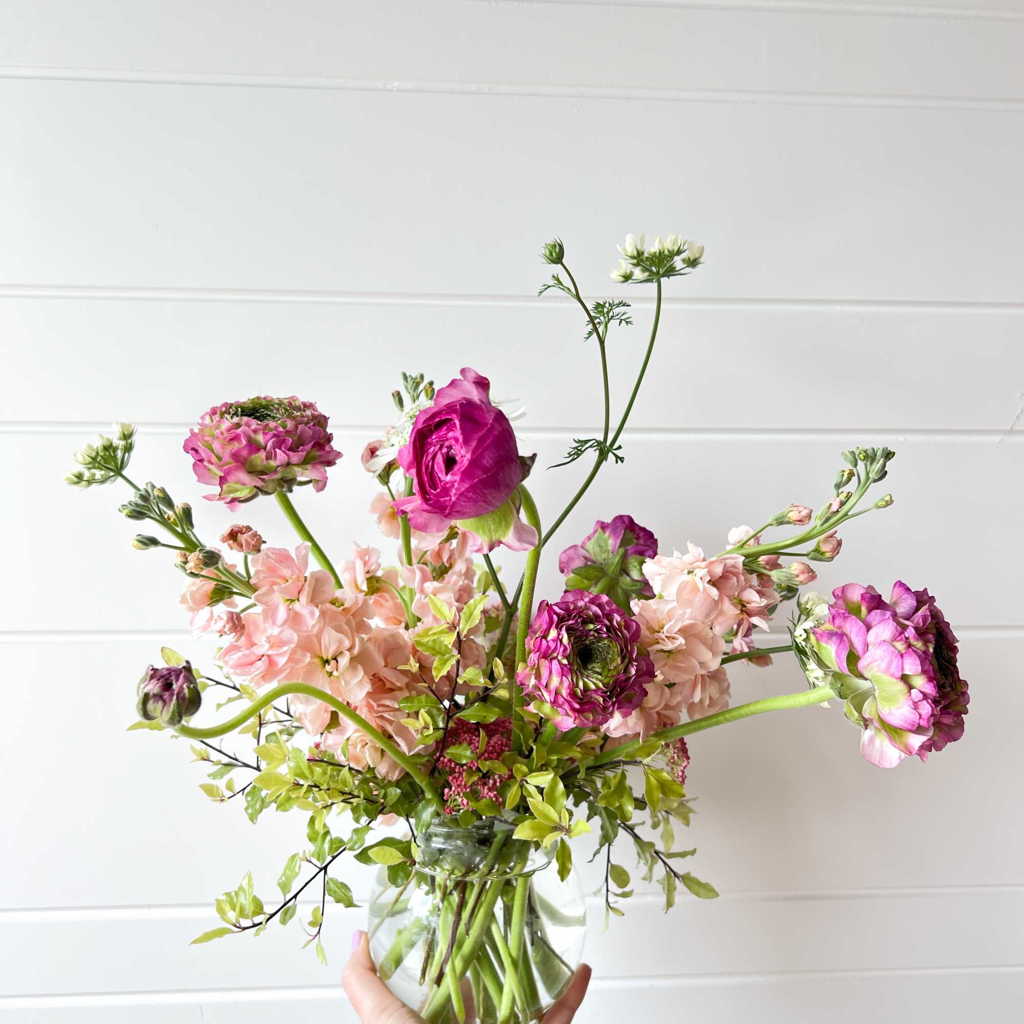 Loose pink and white flowers in a clear glass vase