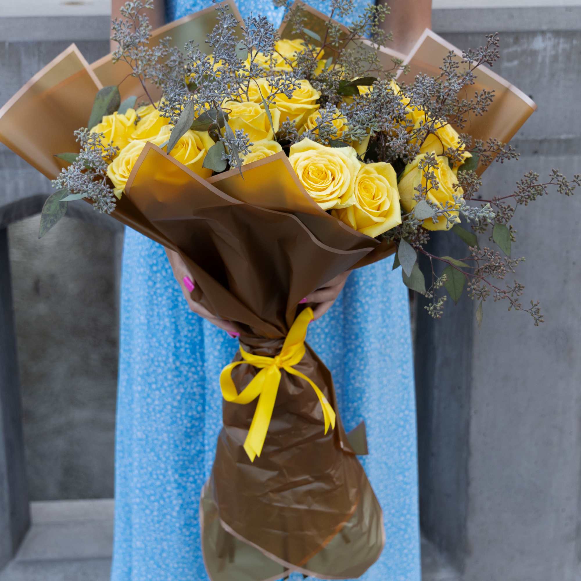 Bouquet of yellow roses wrapped in brown paper with a yellow ribbon