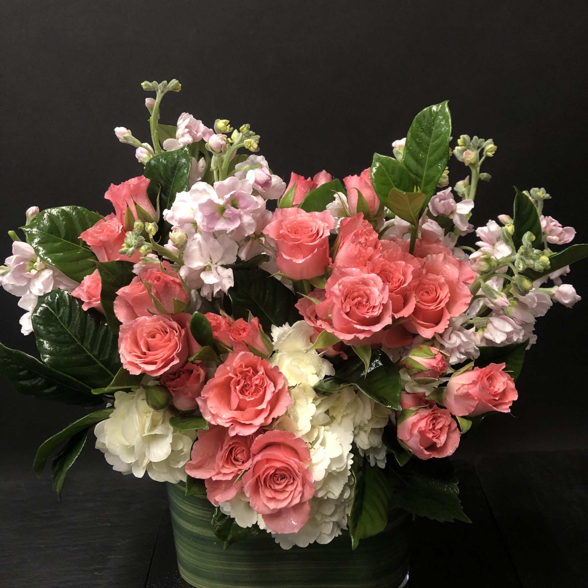 Pink roses and white blooms arranged in a glass vase