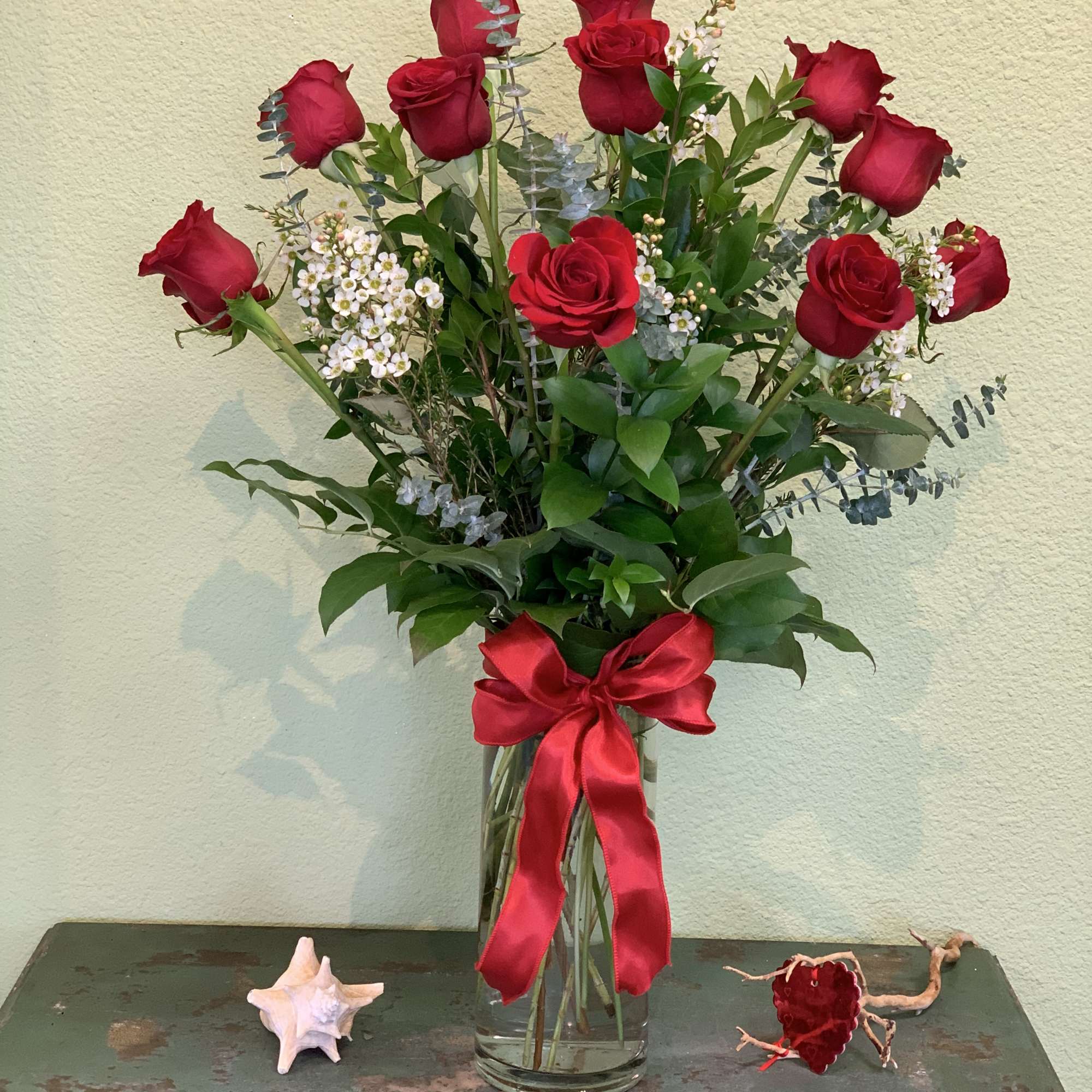 Tall bouquet of red roses in a glass vase with a red ribbon