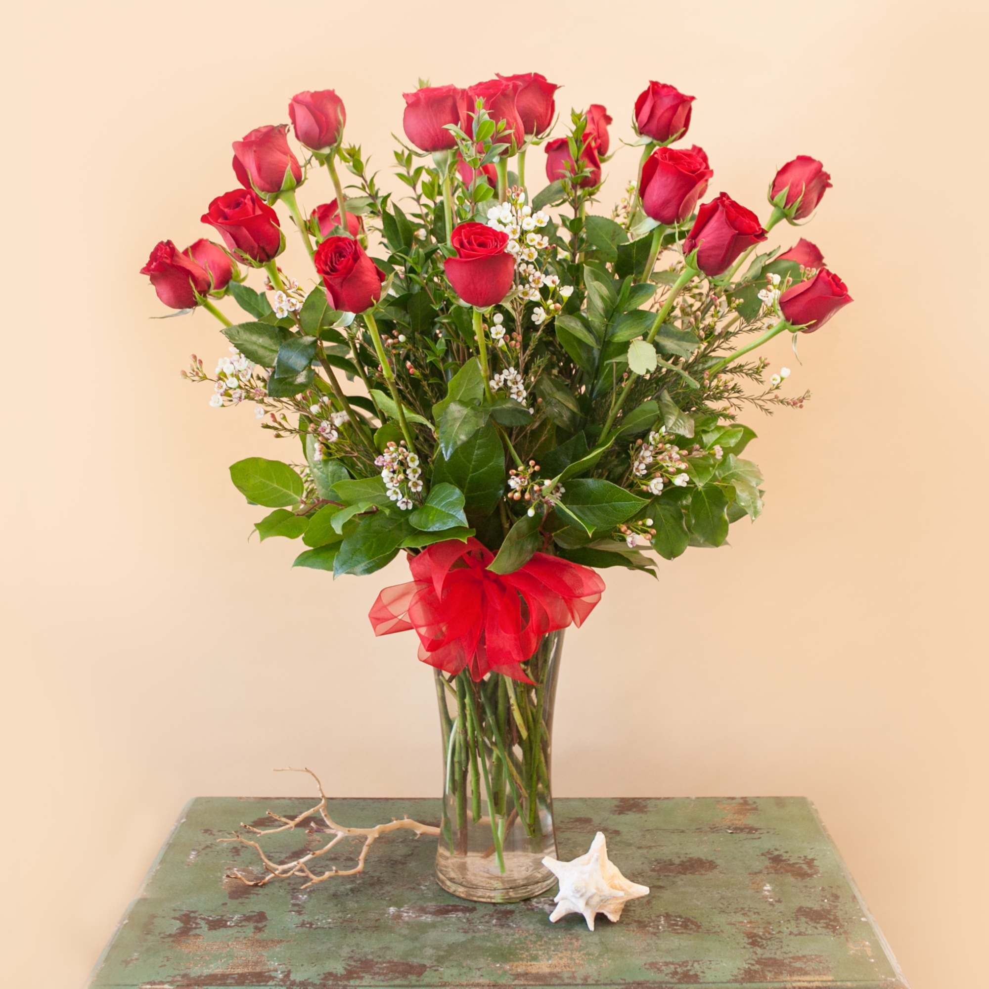 Bouquet of red roses in a clear glass vase with a red ribbon