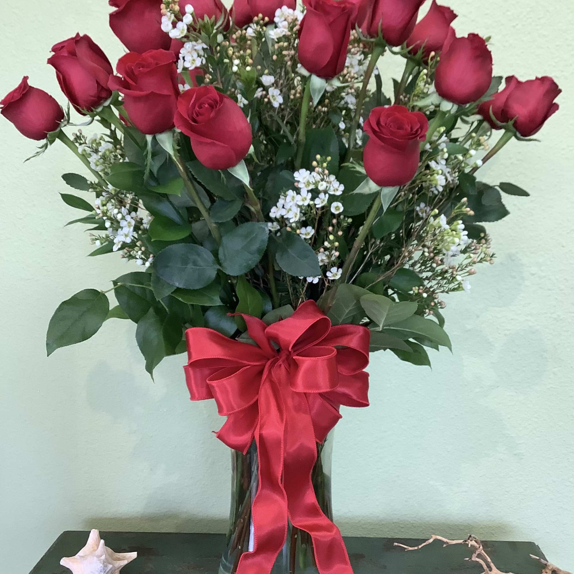 Bouquet of red roses with white filler flowers in a glass vase and red ribbon