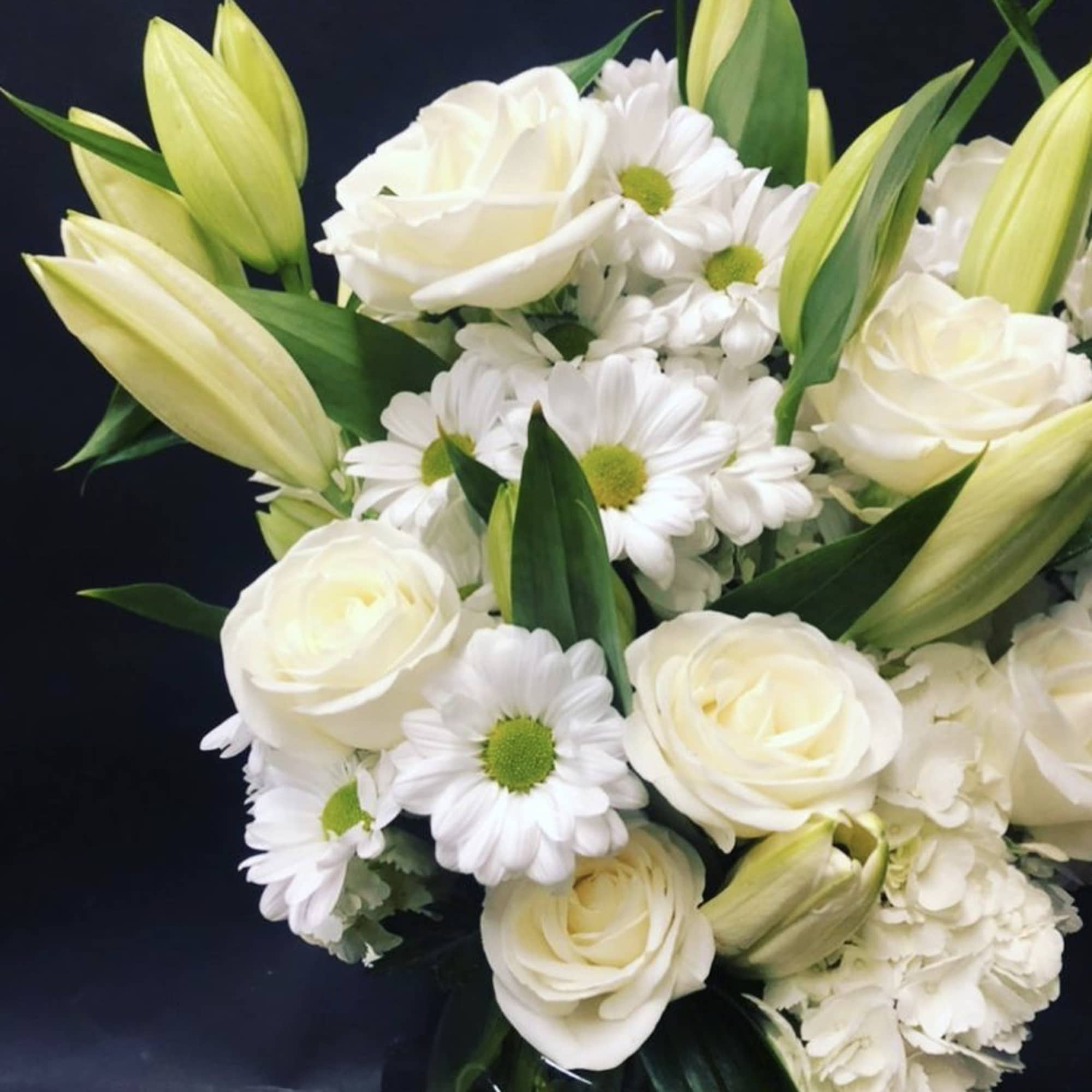 White roses and daisies with pale lily buds in a bouquet