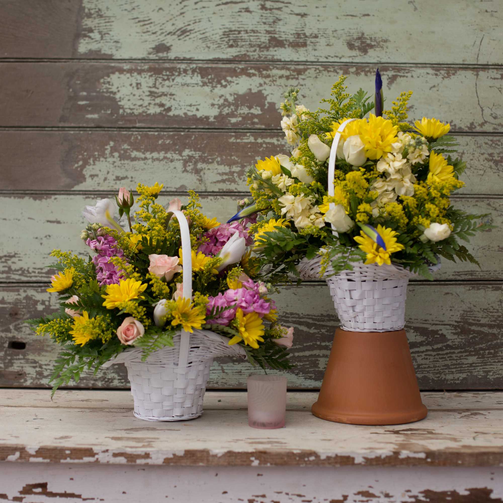 Two basket flower arrangements with yellow and pink blooms