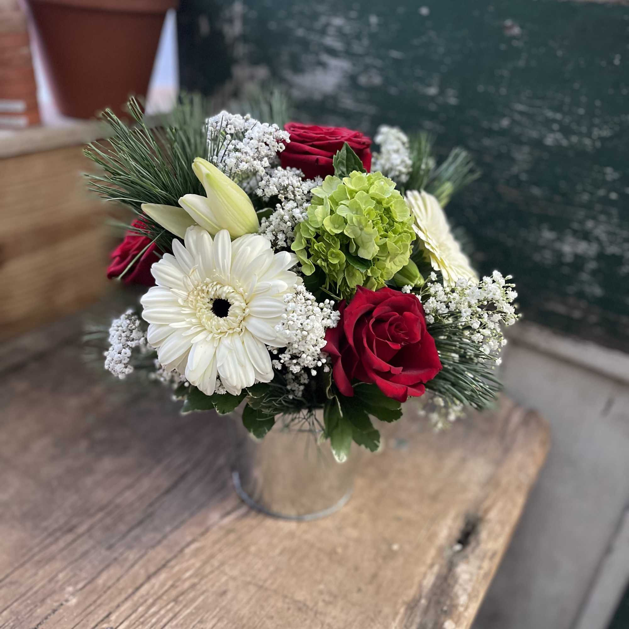Bouquet of red roses, white gerbera daisies, and green hydrangea in a metal vase