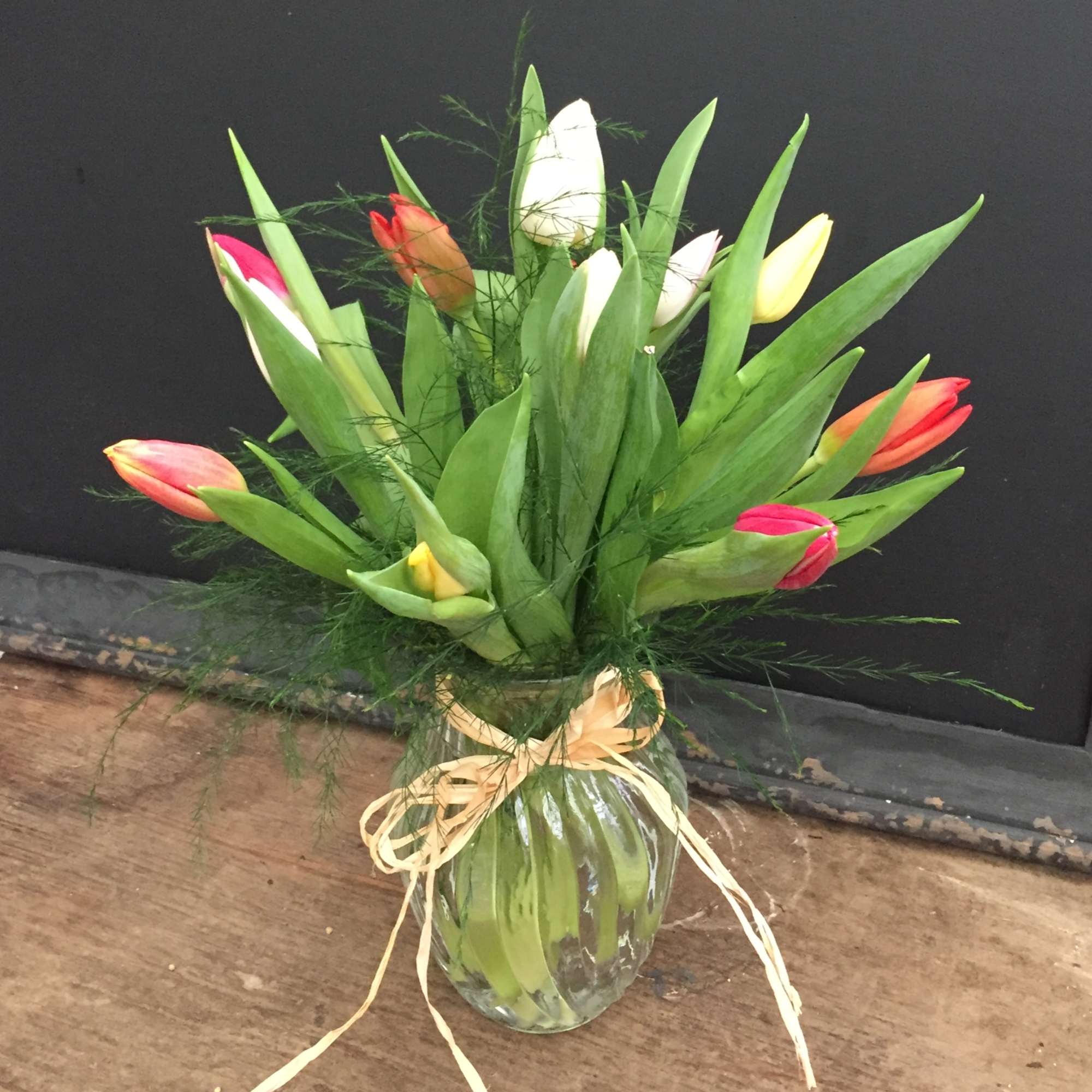 Tulip bouquet in a glass vase with a ribbon bow