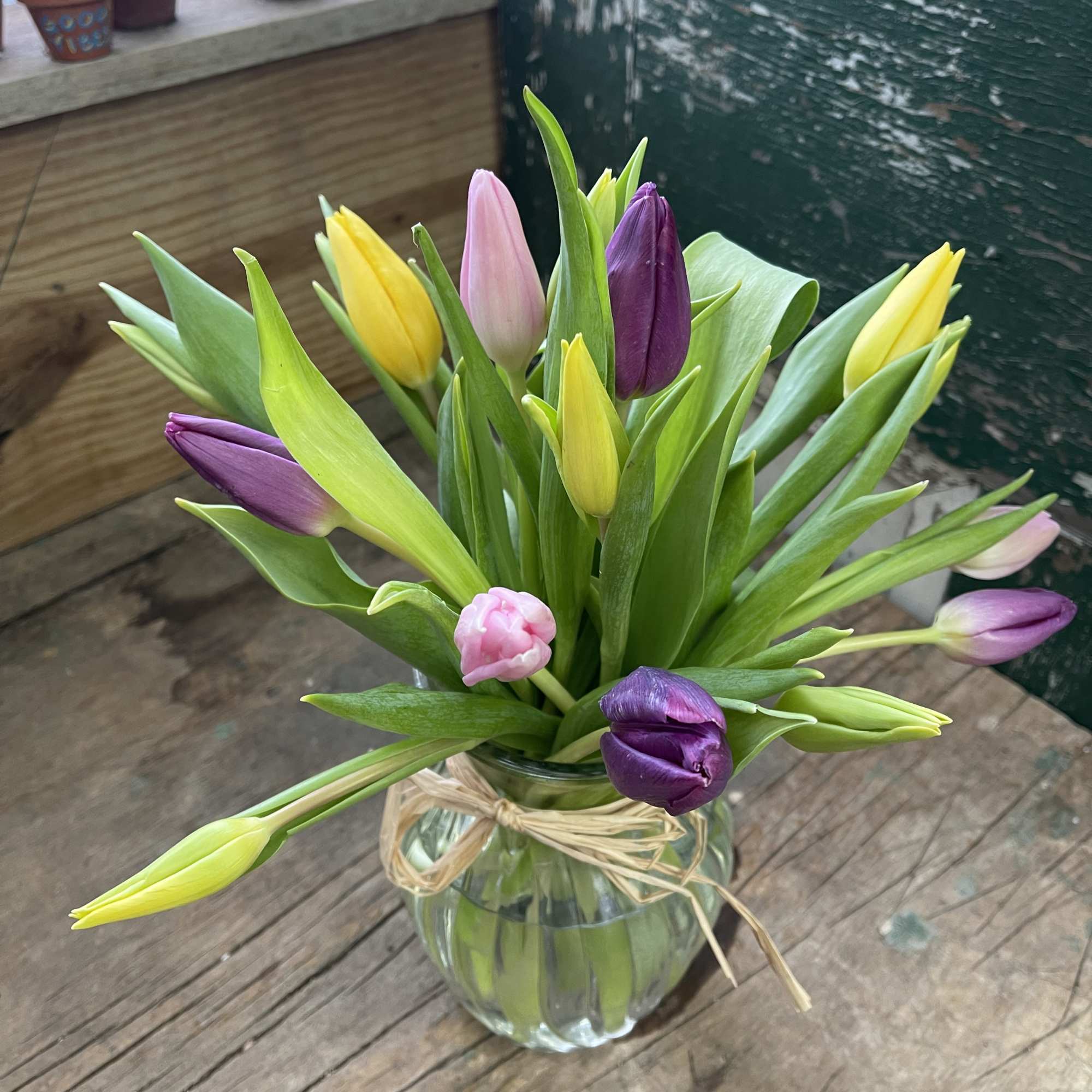 Mixed tulips in a clear glass vase tied with raffia