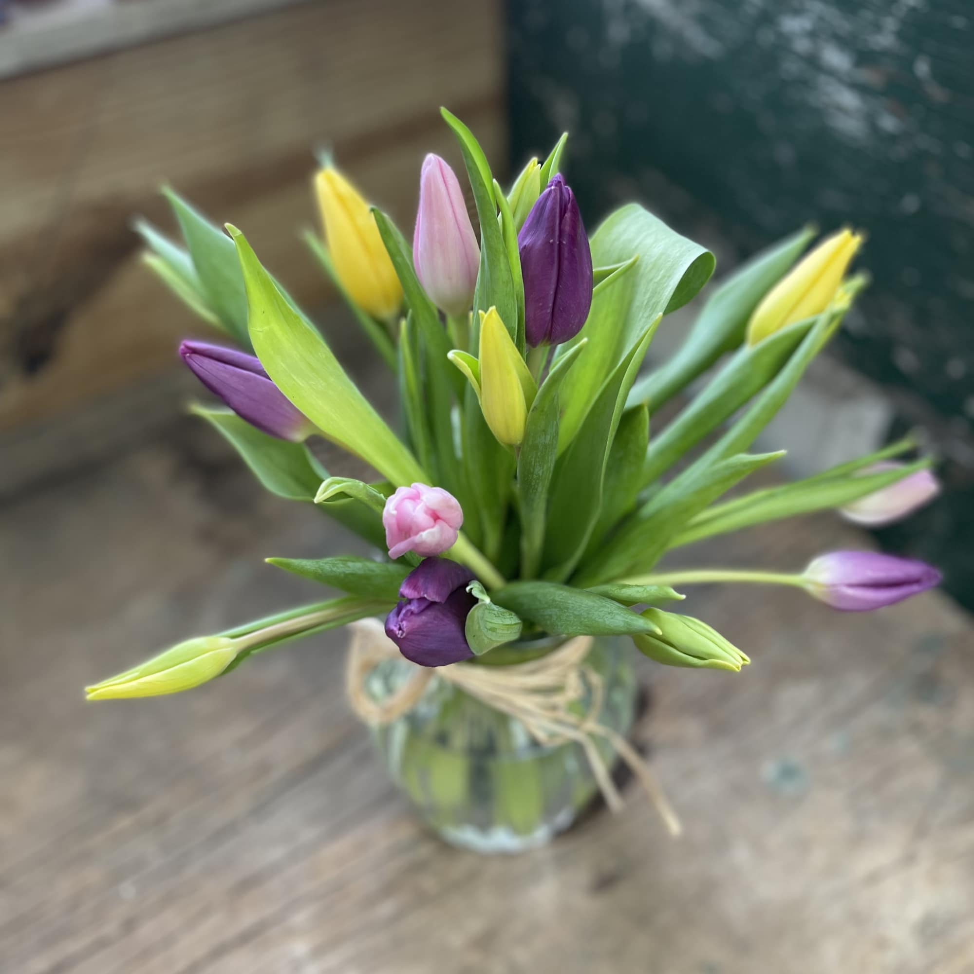 Small bouquet of multicolored tulip buds in a glass vase