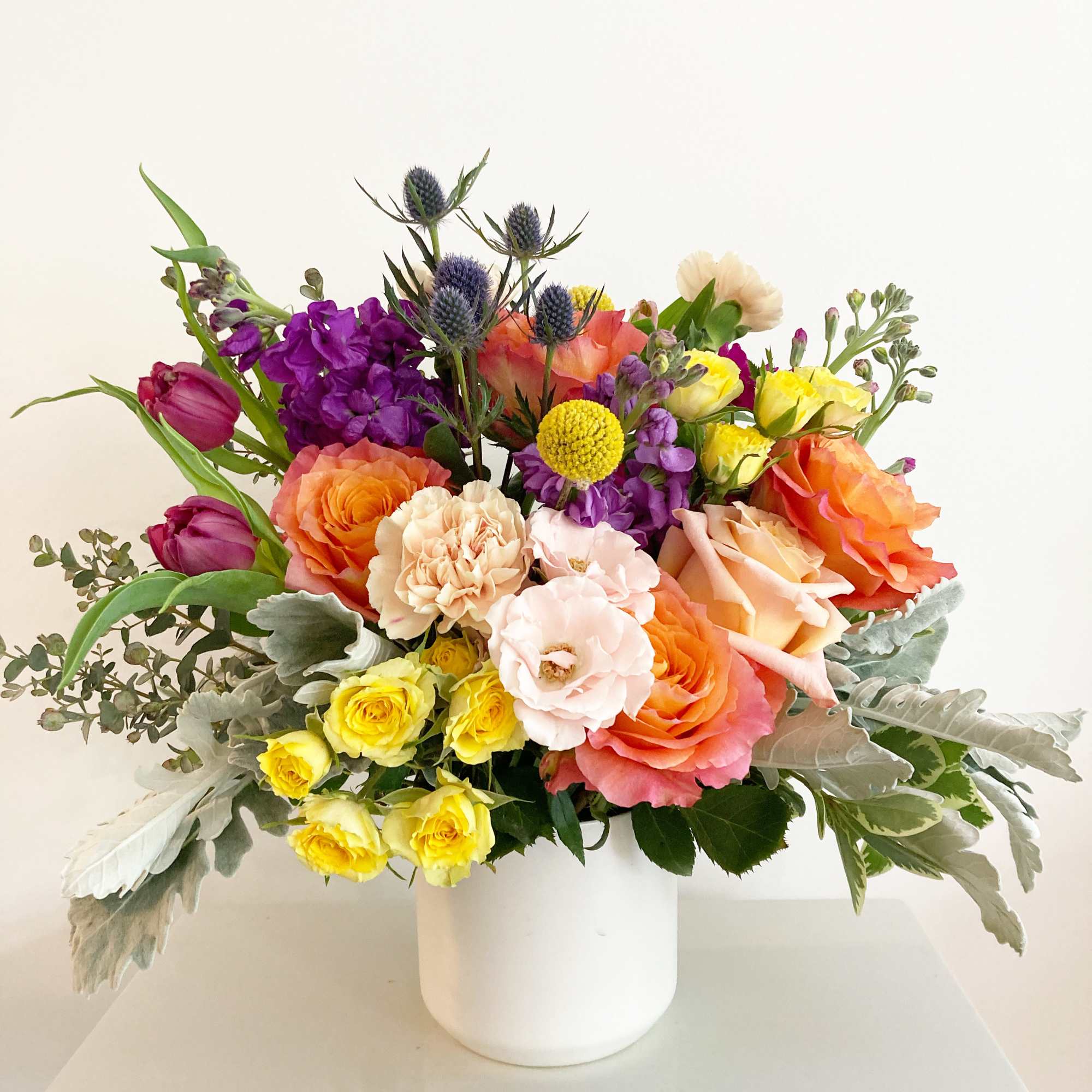 Colorful mixed bouquet in a white vase with roses and tulips
