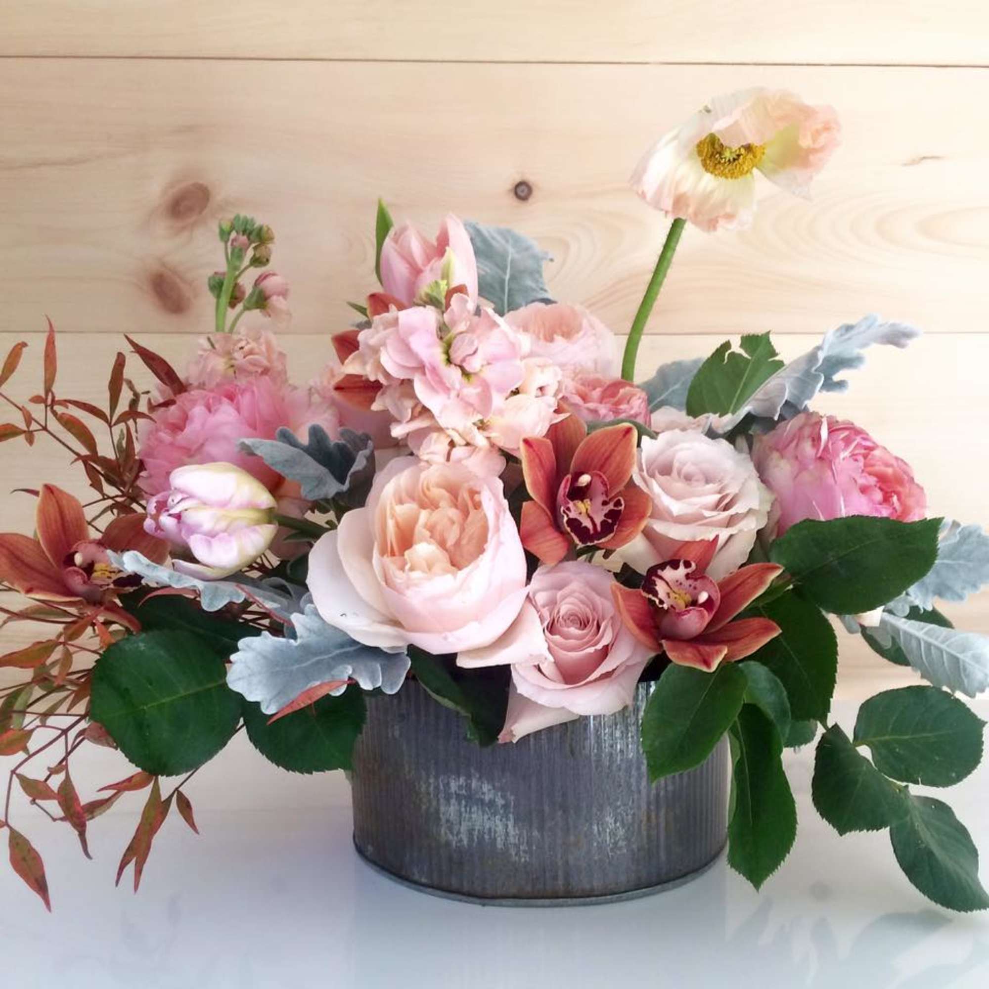Pink and peach floral arrangement in a gray metal container