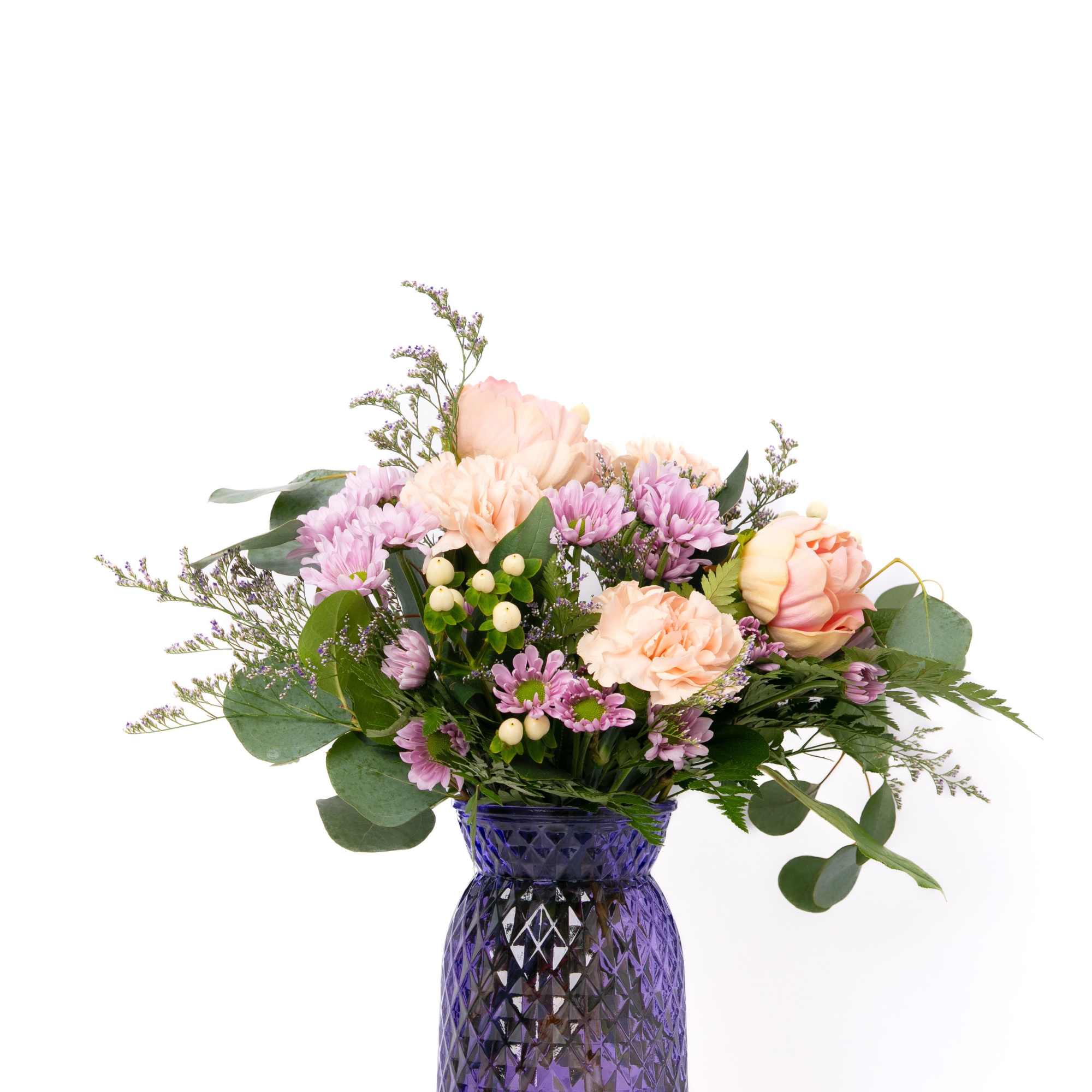 Mixed bouquet of peach roses and carnations with lavender mums in a purple glass vase