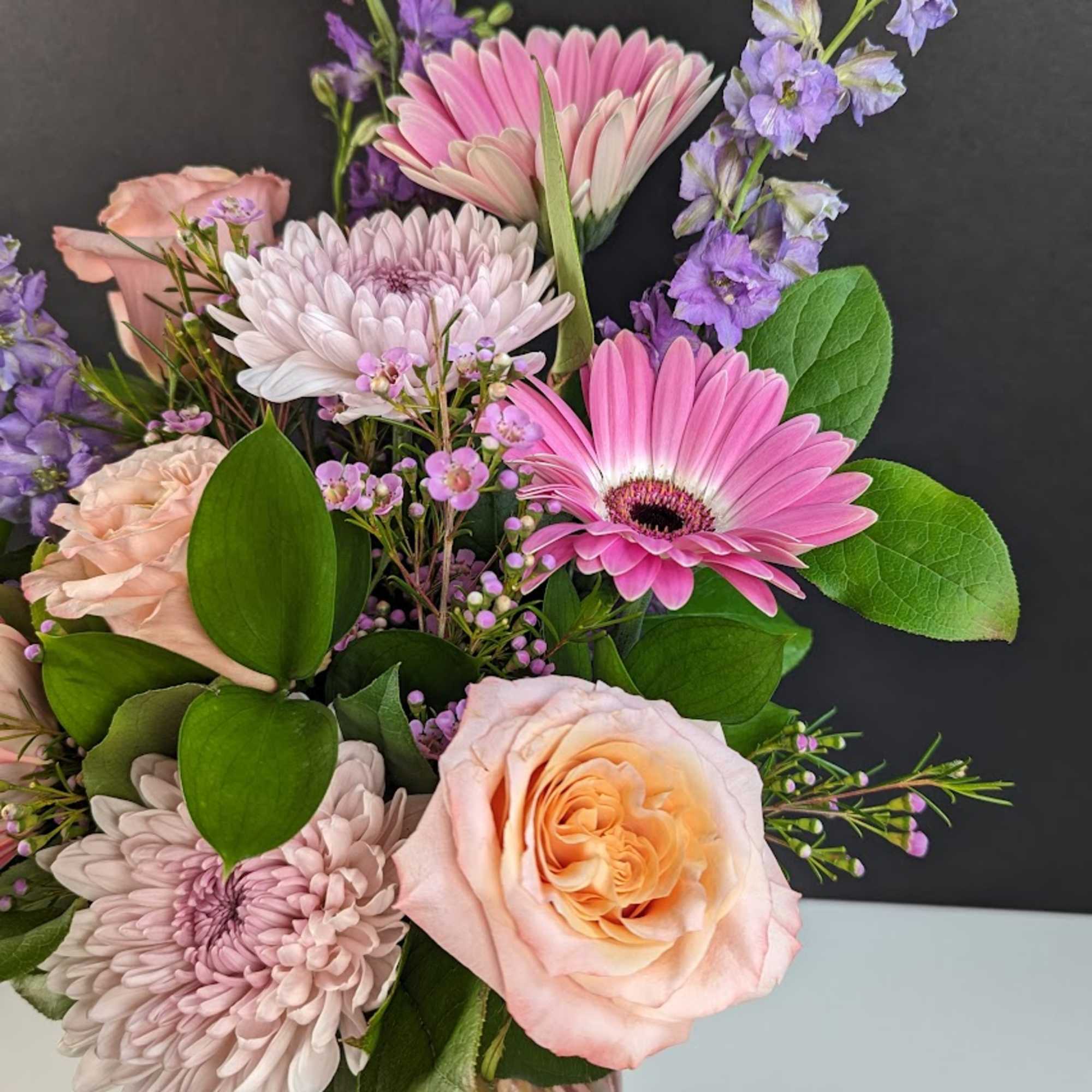 Pink and lavender bouquet with roses and daisies in a glass vase