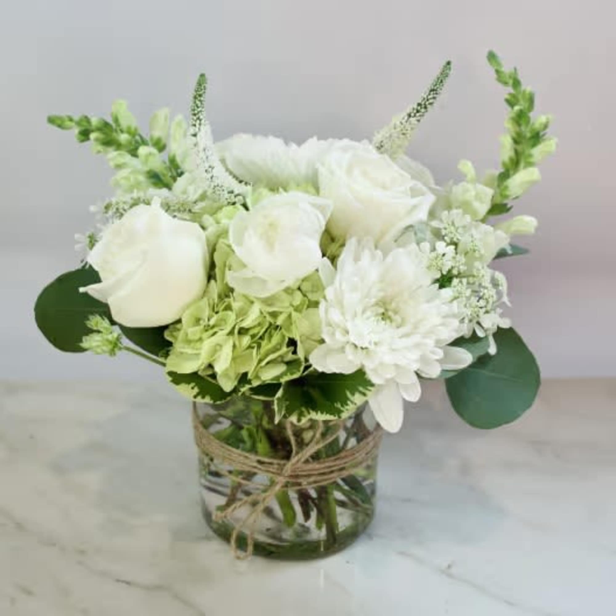 White roses and chrysanthemums in a glass vase with twine
