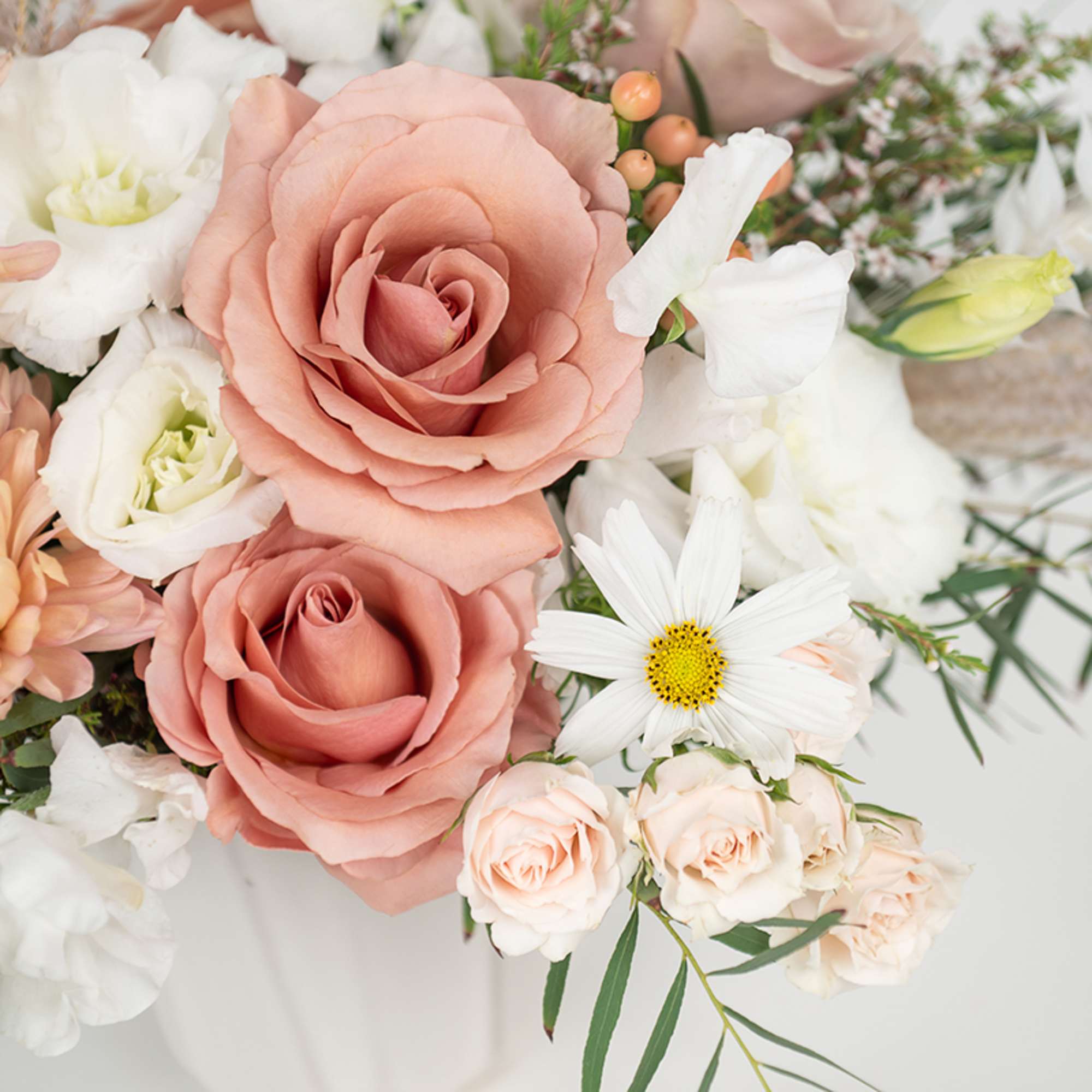 Arrangement of peach roses with white blooms in a soft pastel bouquet