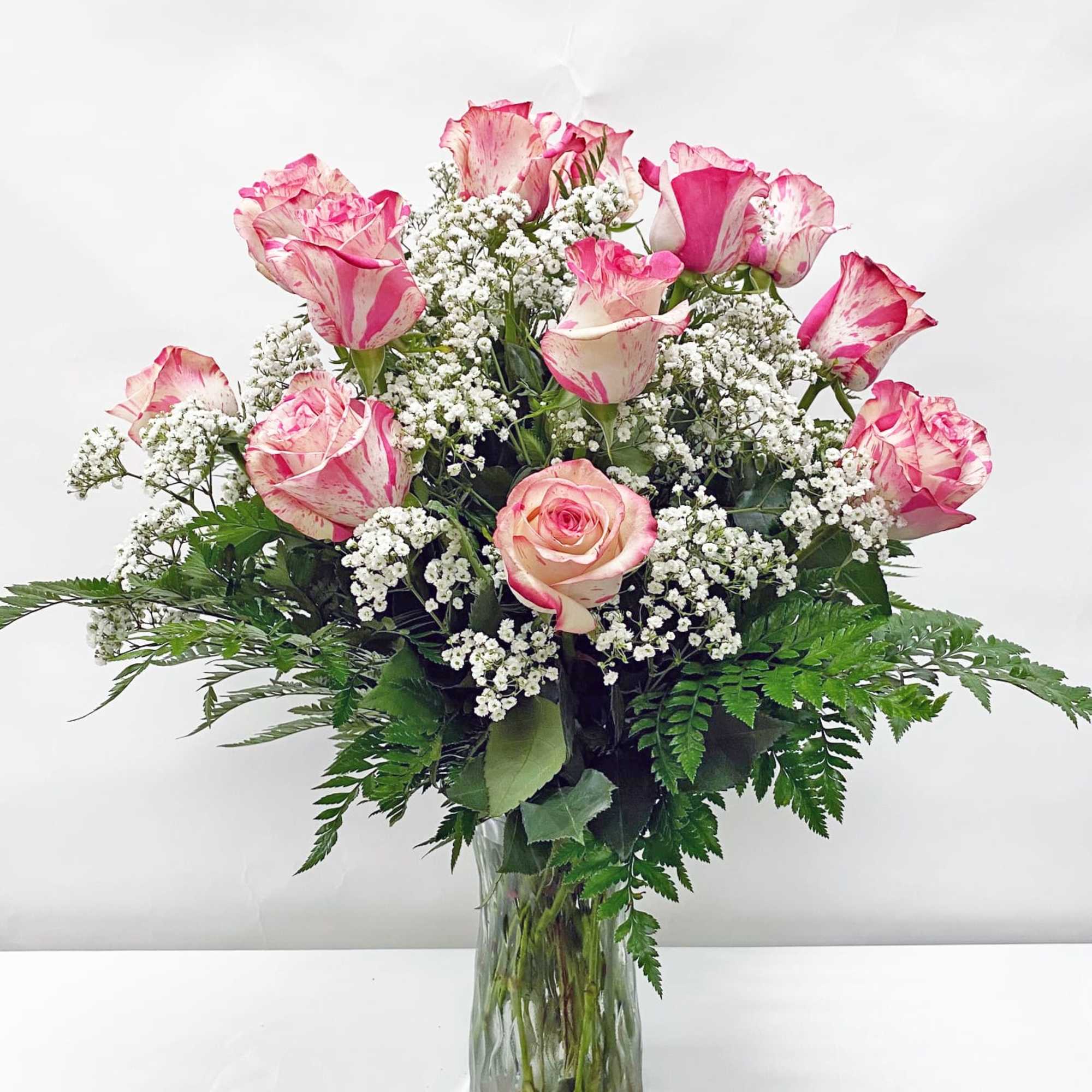 Tall vase arrangement of pink and white roses with small white filler flowers