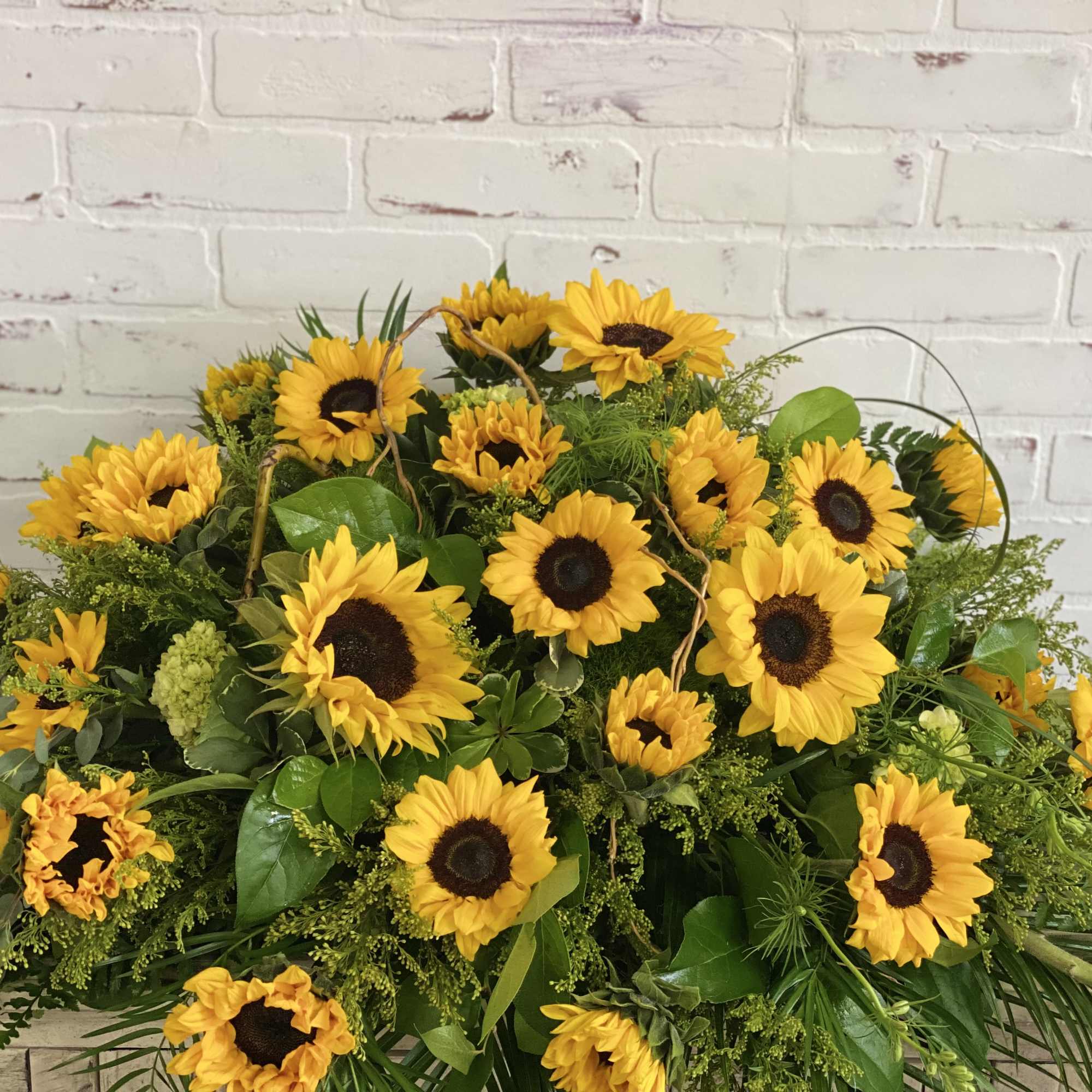 Large arrangement of yellow sunflowers with mixed greenery