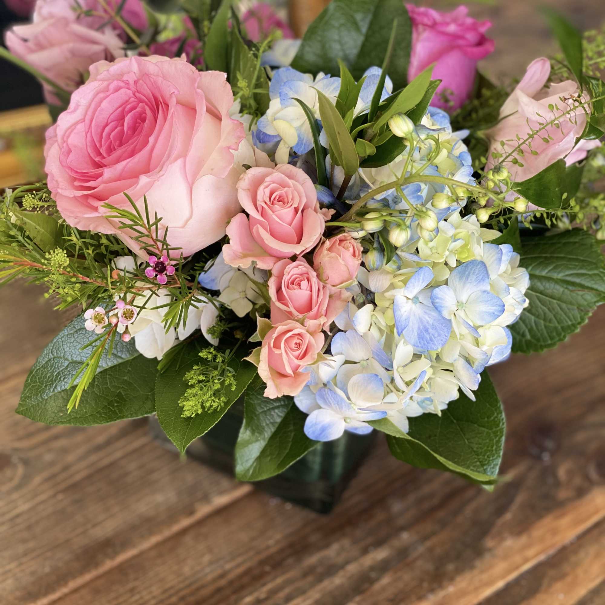 Pink roses and blue-white hydrangeas in a glass vase