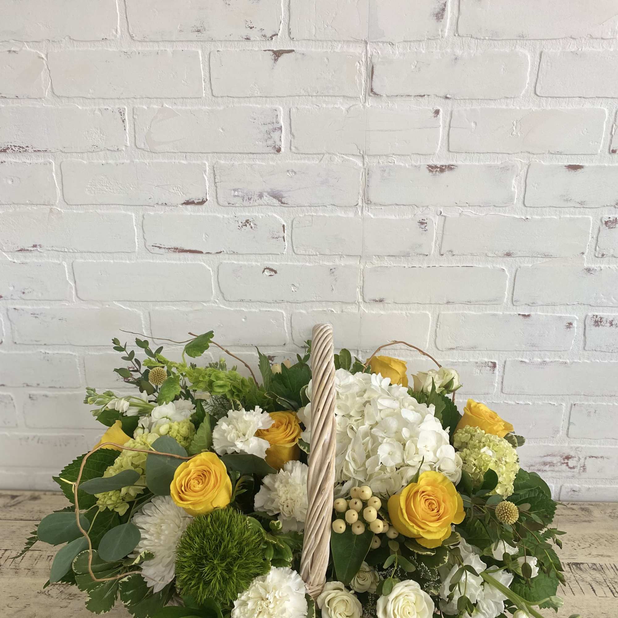 Basket arrangement of yellow and white flowers with greenery