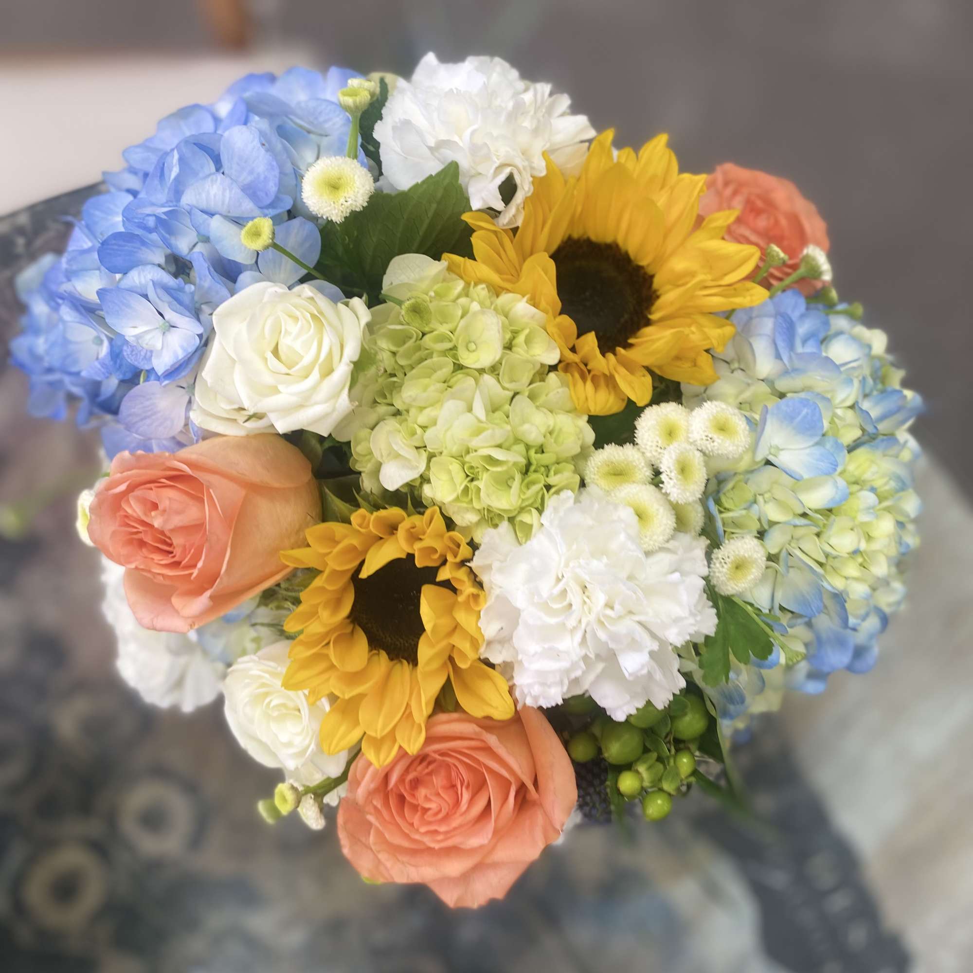 Bouquet of blue hydrangeas, sunflowers, and peach roses
