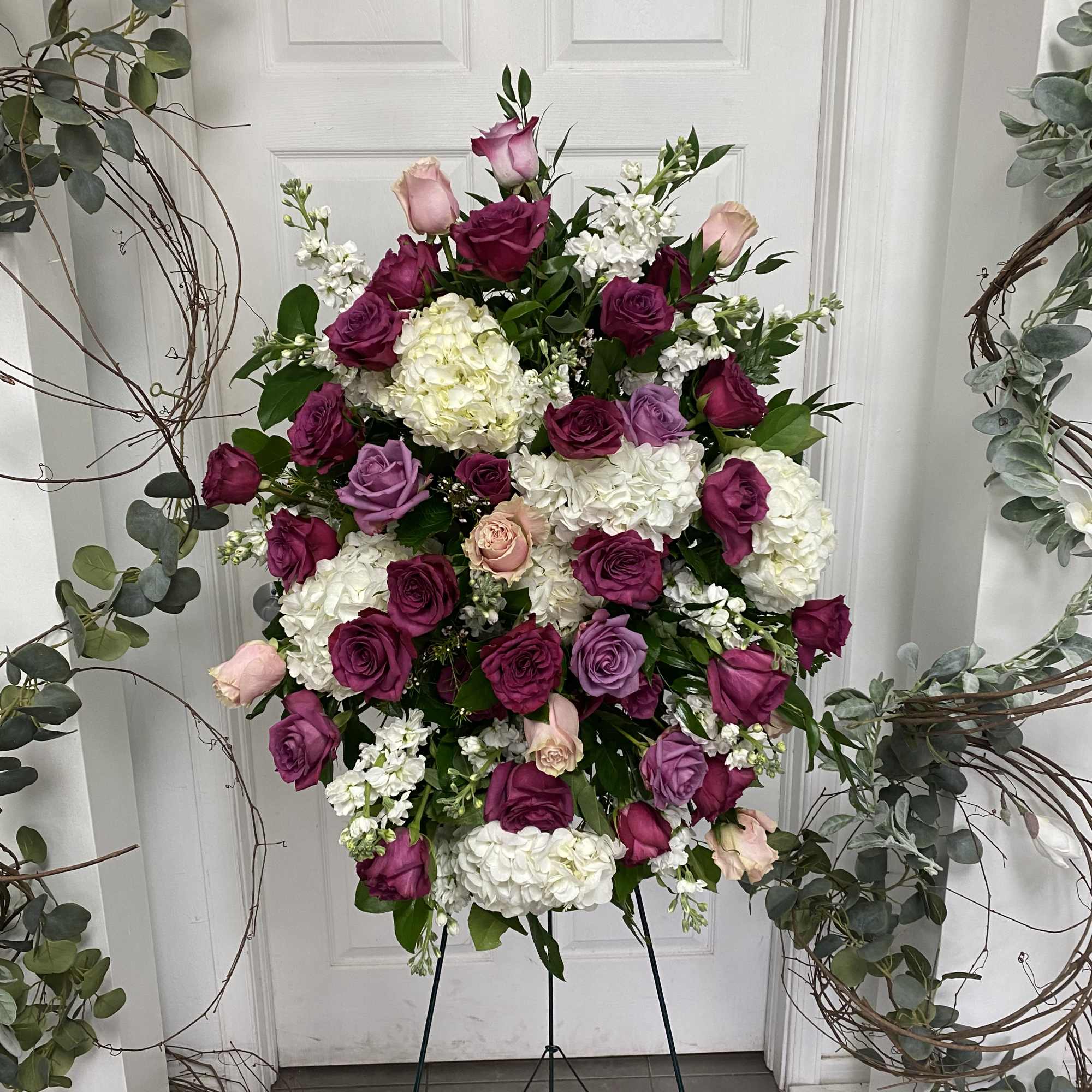 Large standing floral spray with pink and purple roses and white blooms