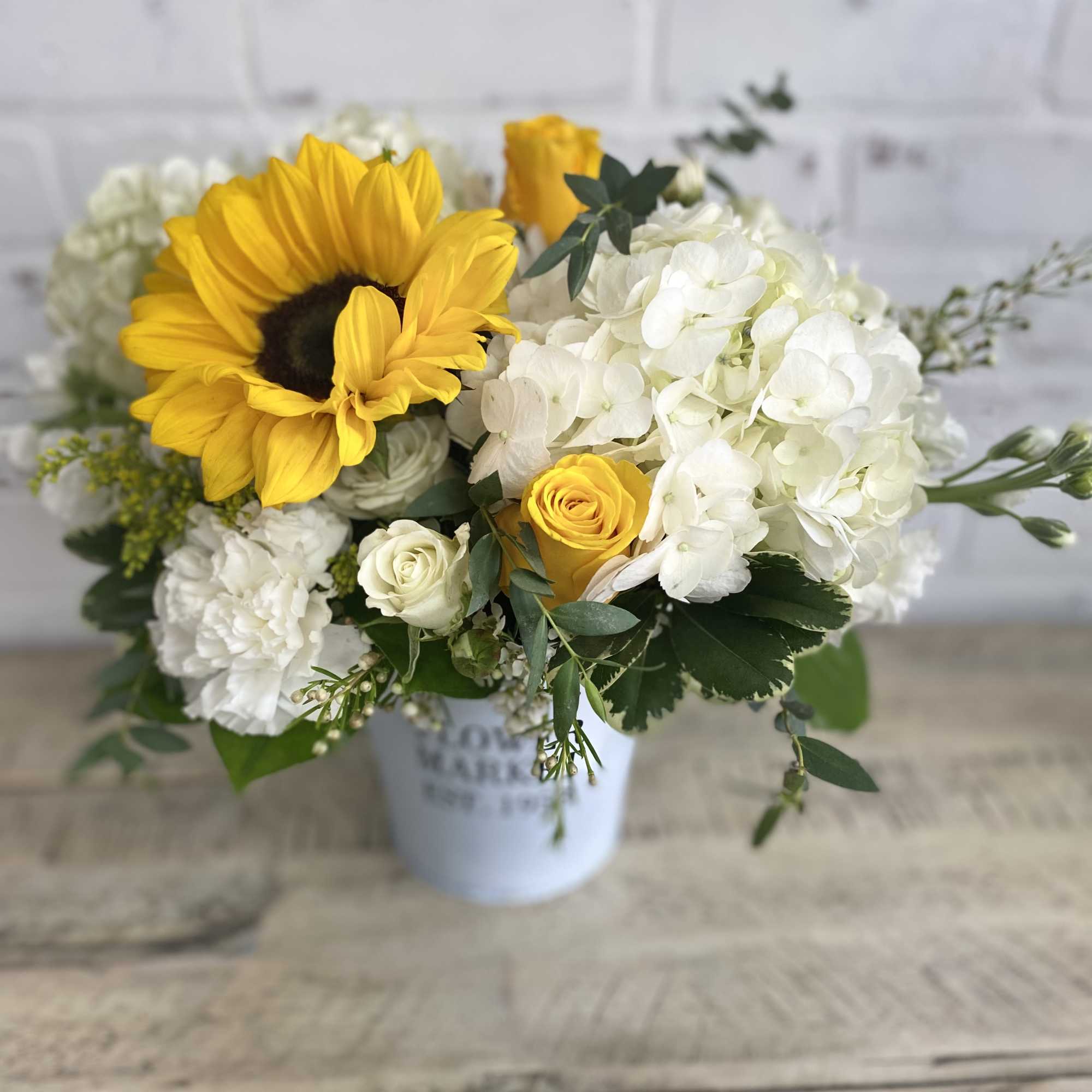 Sunflower and white hydrangea bouquet in a white container