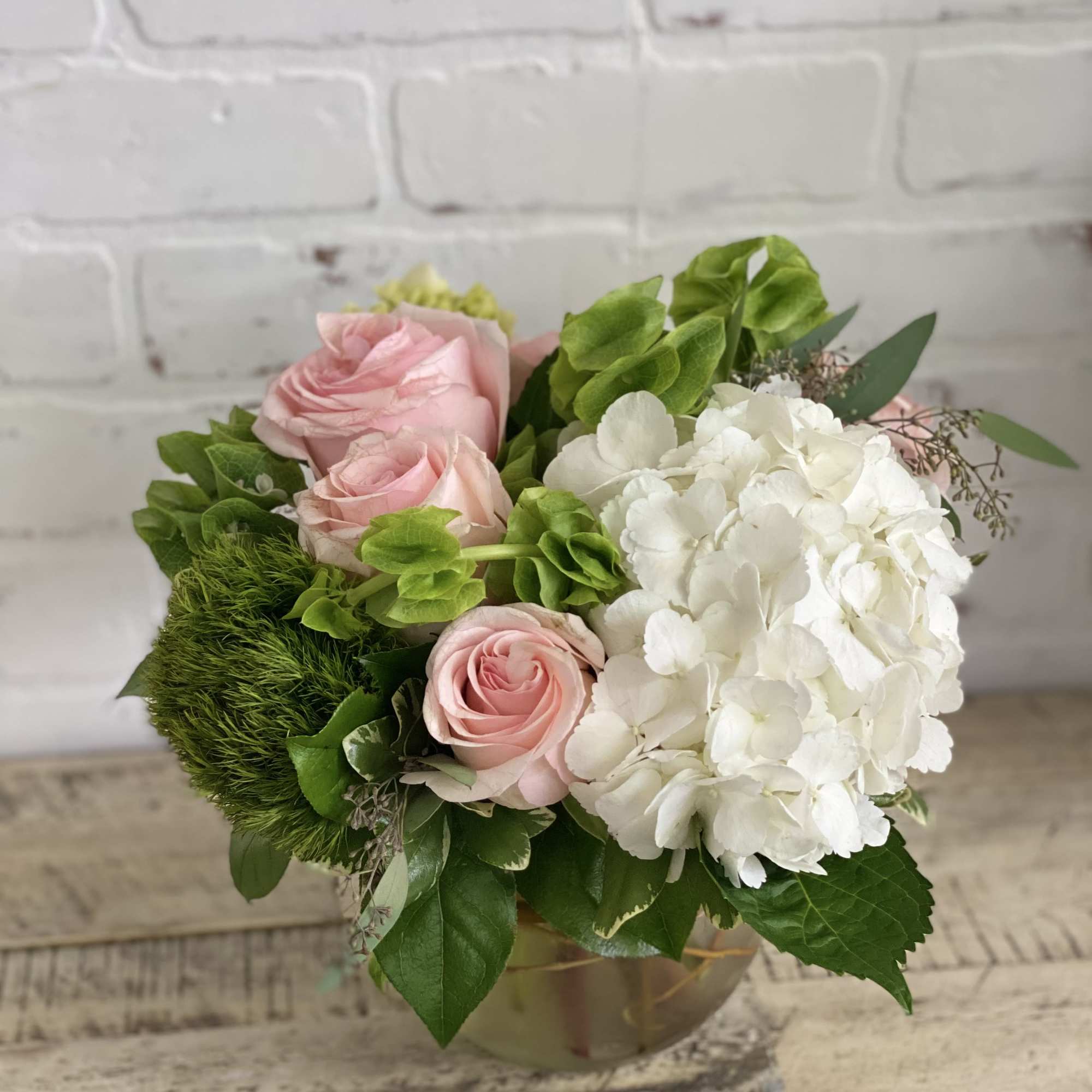 Pink roses and white hydrangea in a low glass vase
