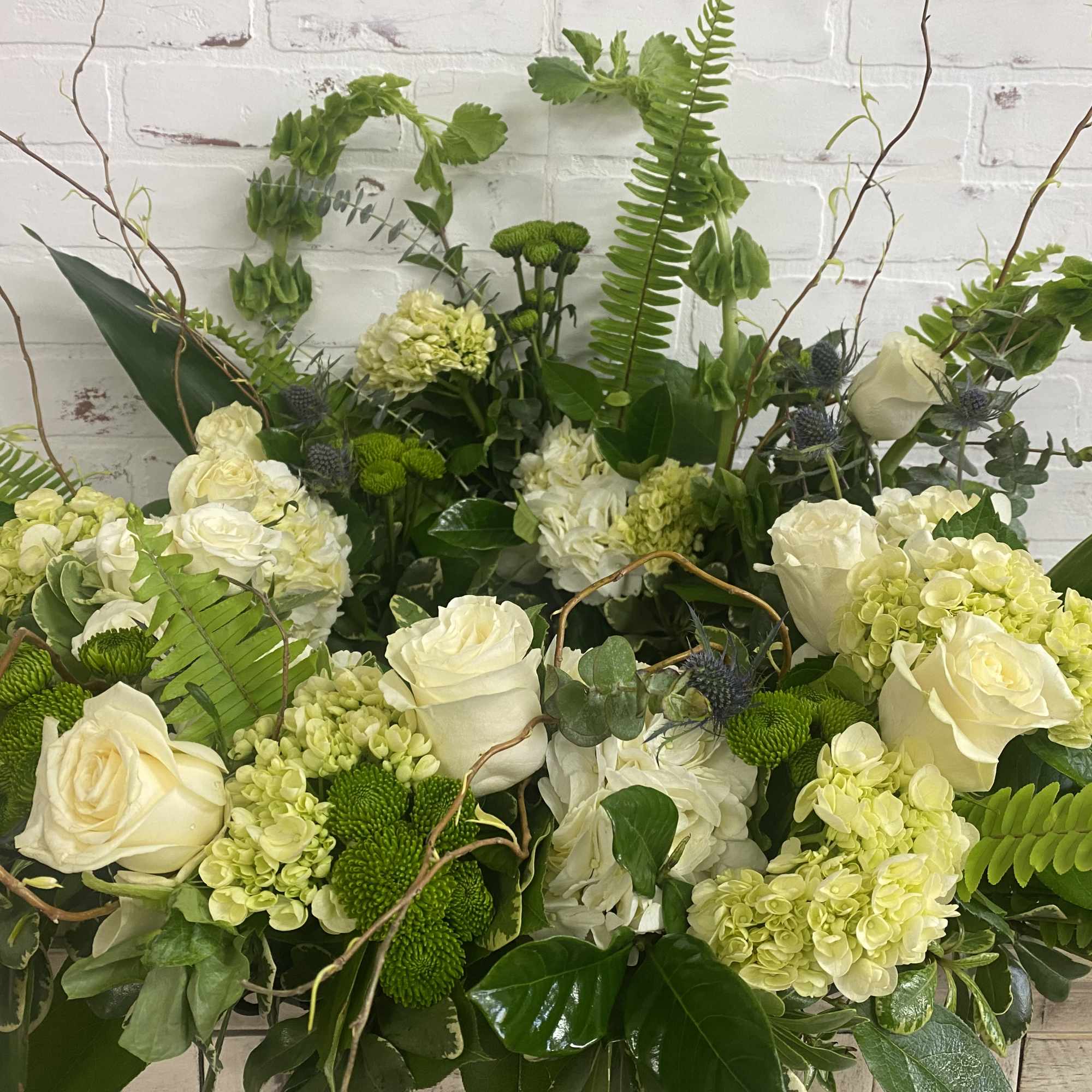 Large green and white floral arrangement with roses and hydrangeas