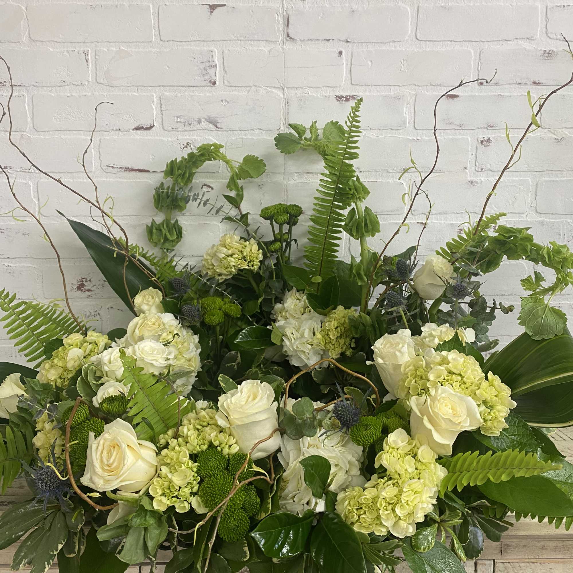 Large green and white floral arrangement with roses and hydrangeas