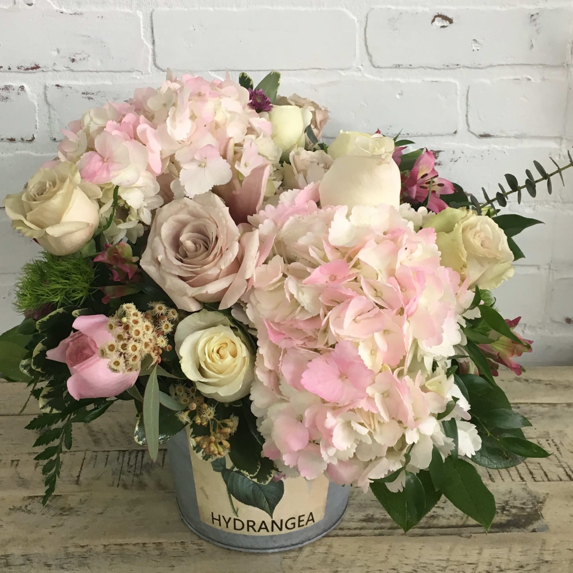 Pink and cream bouquet in a metal bucket with hydrangeas and roses