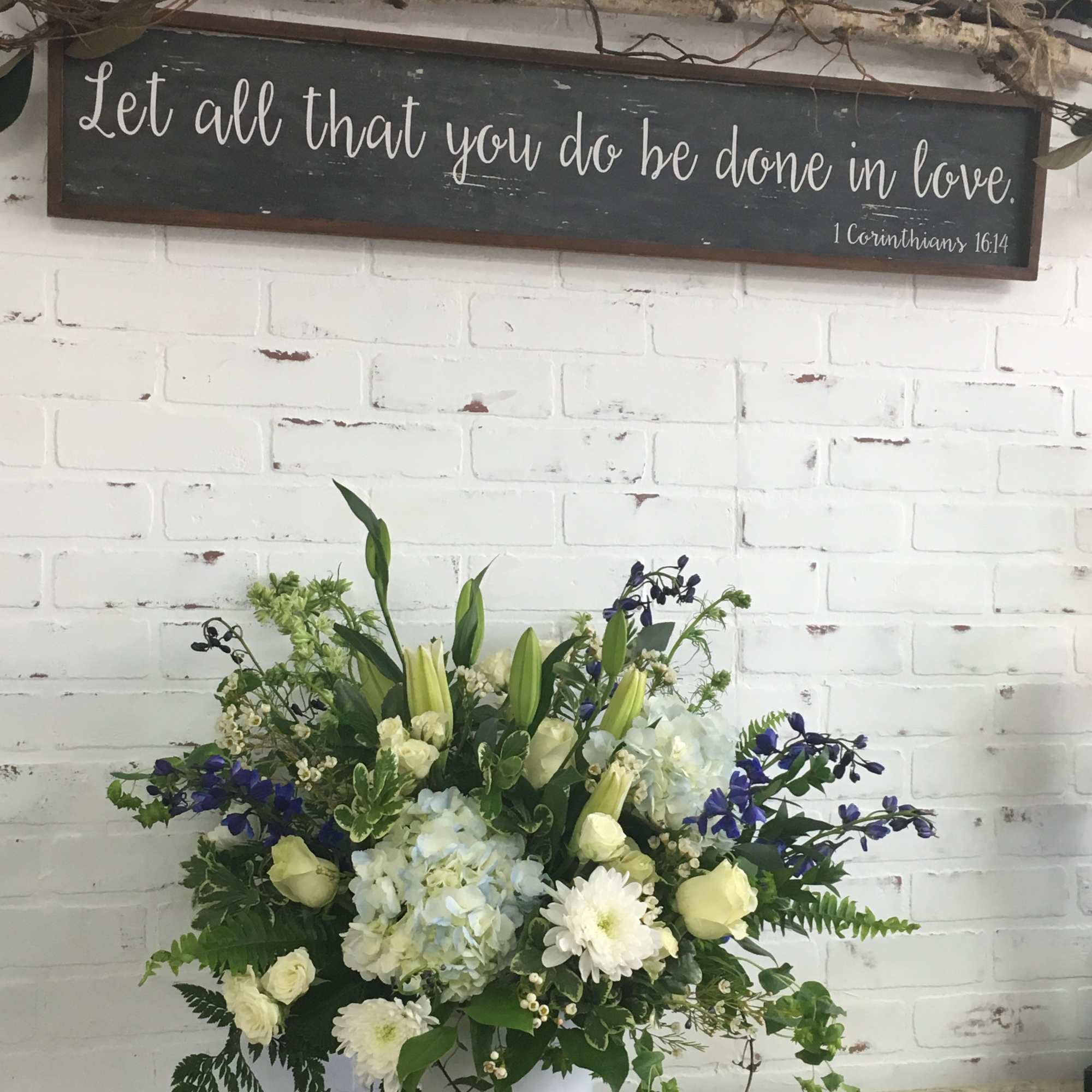 White and blue floral arrangement in a white bucket vase