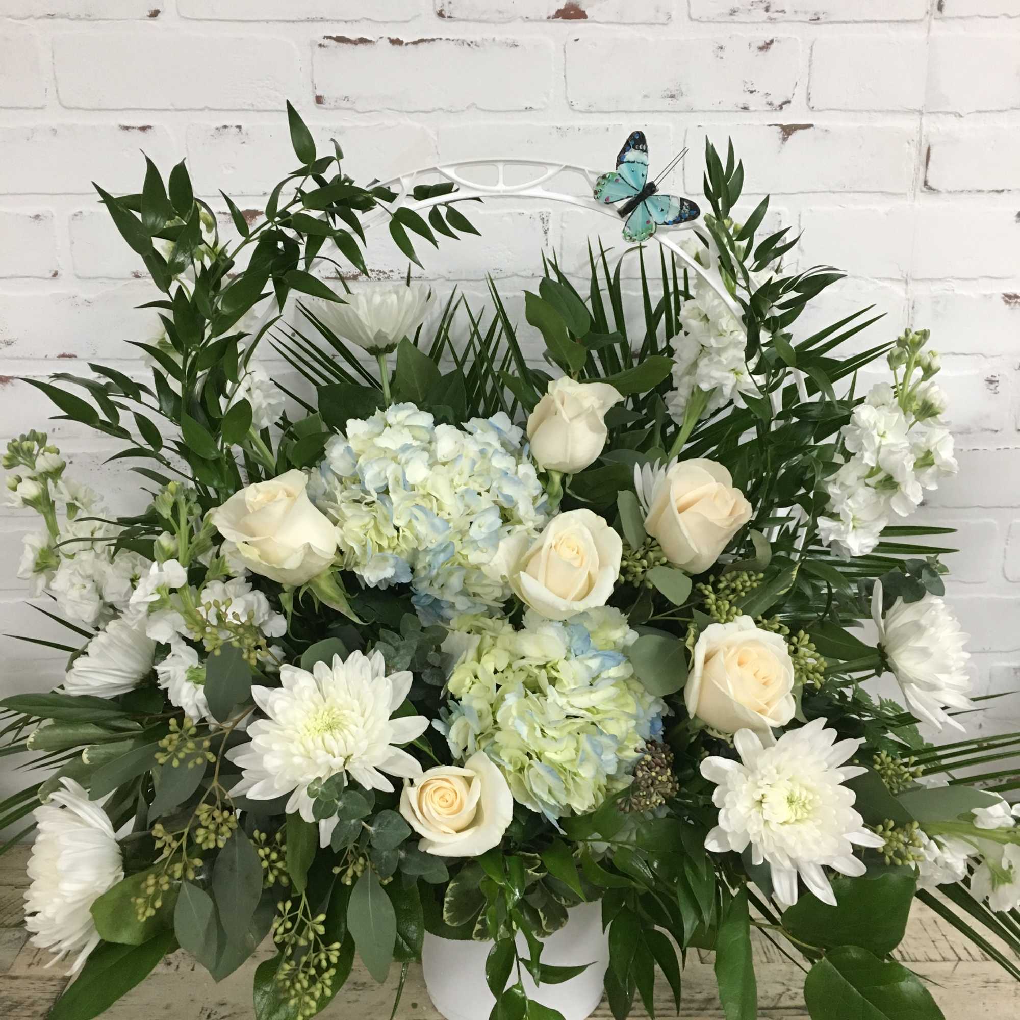 White roses and hydrangeas in a white container with greenery