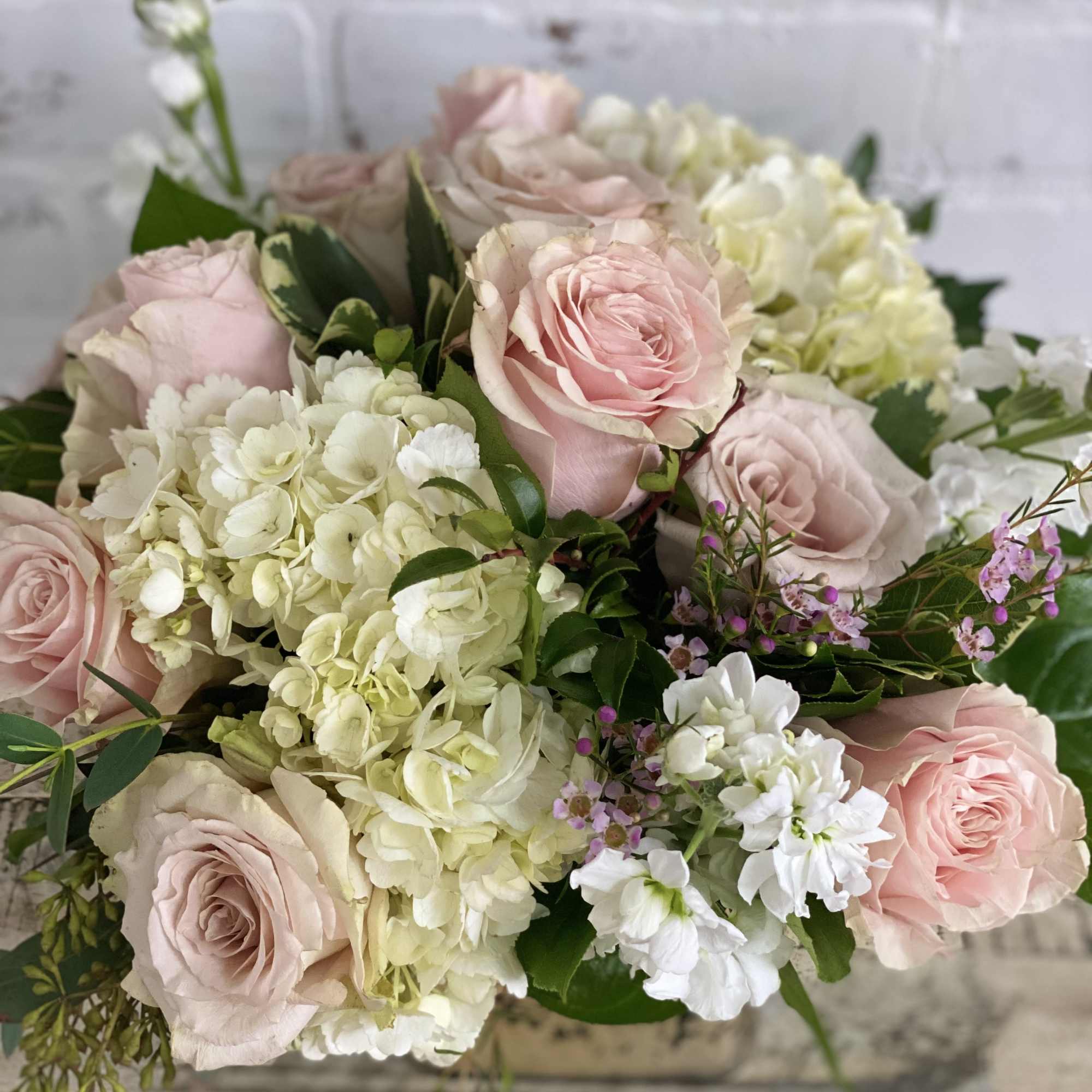 Arrangement of blush pink roses and white hydrangeas in a low vase