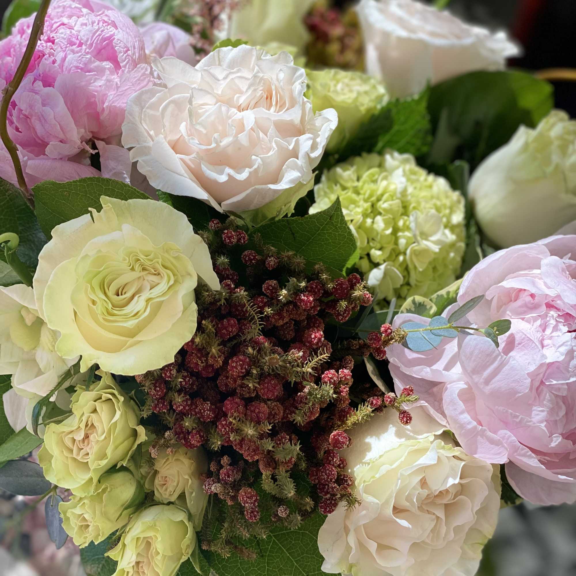Arrangement of blush roses, green hydrangea, and pink peonies in a vase