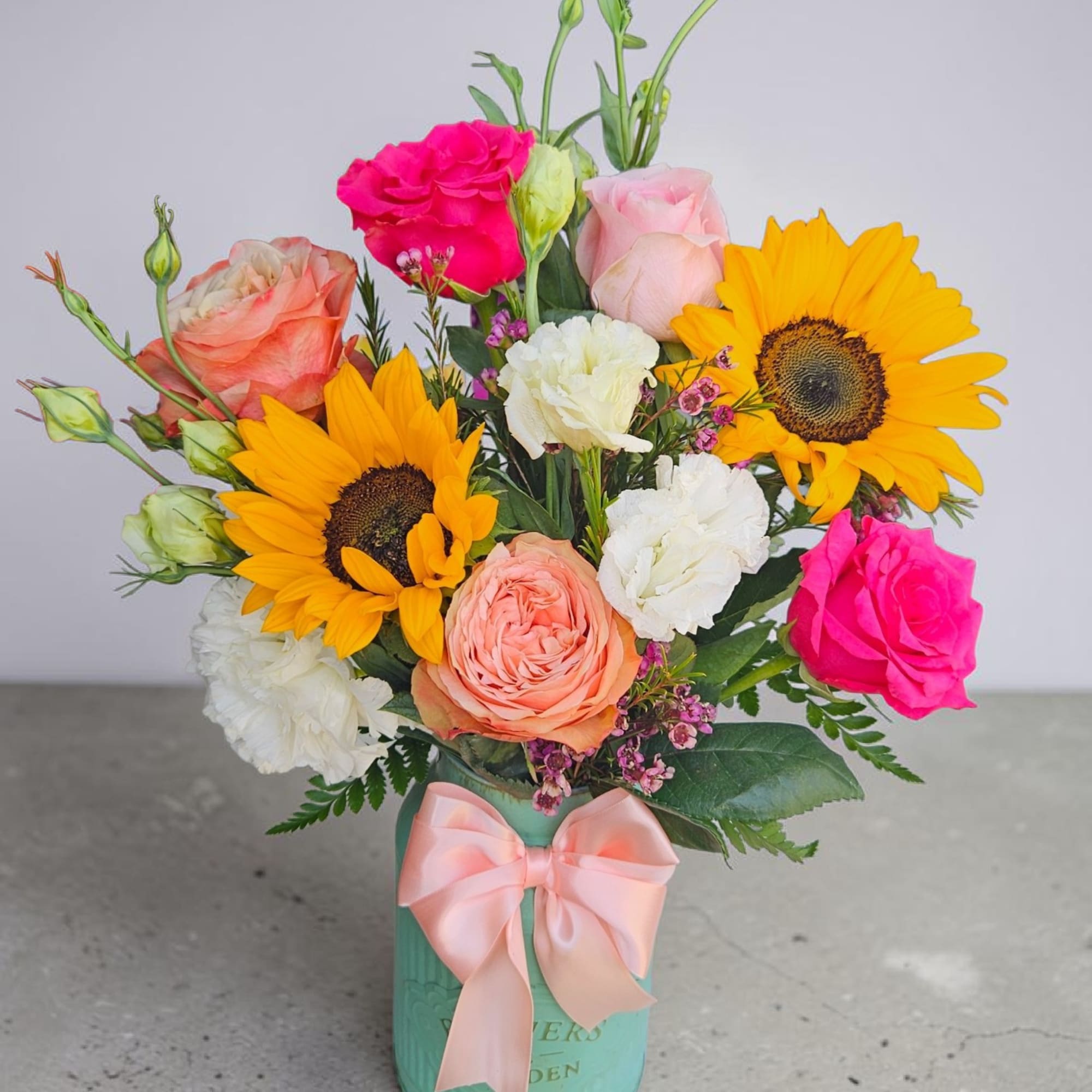 Bright yellow sunflowers burst from a compact, rounded flower arrangement that feels