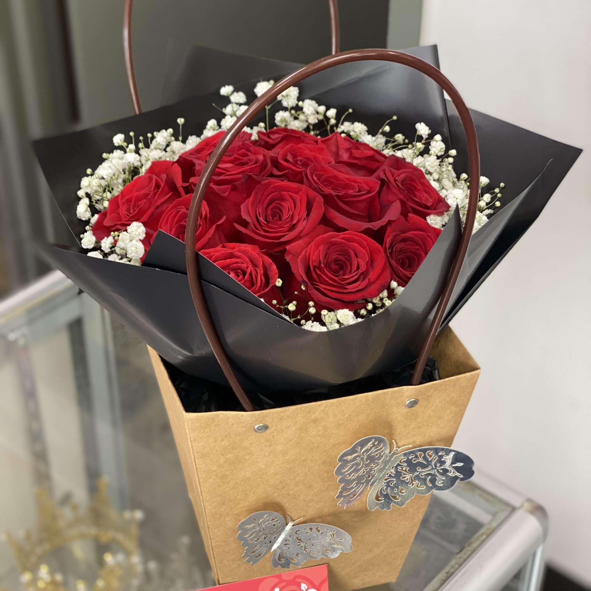 Red rose bouquet with baby's breath in a brown gift bag