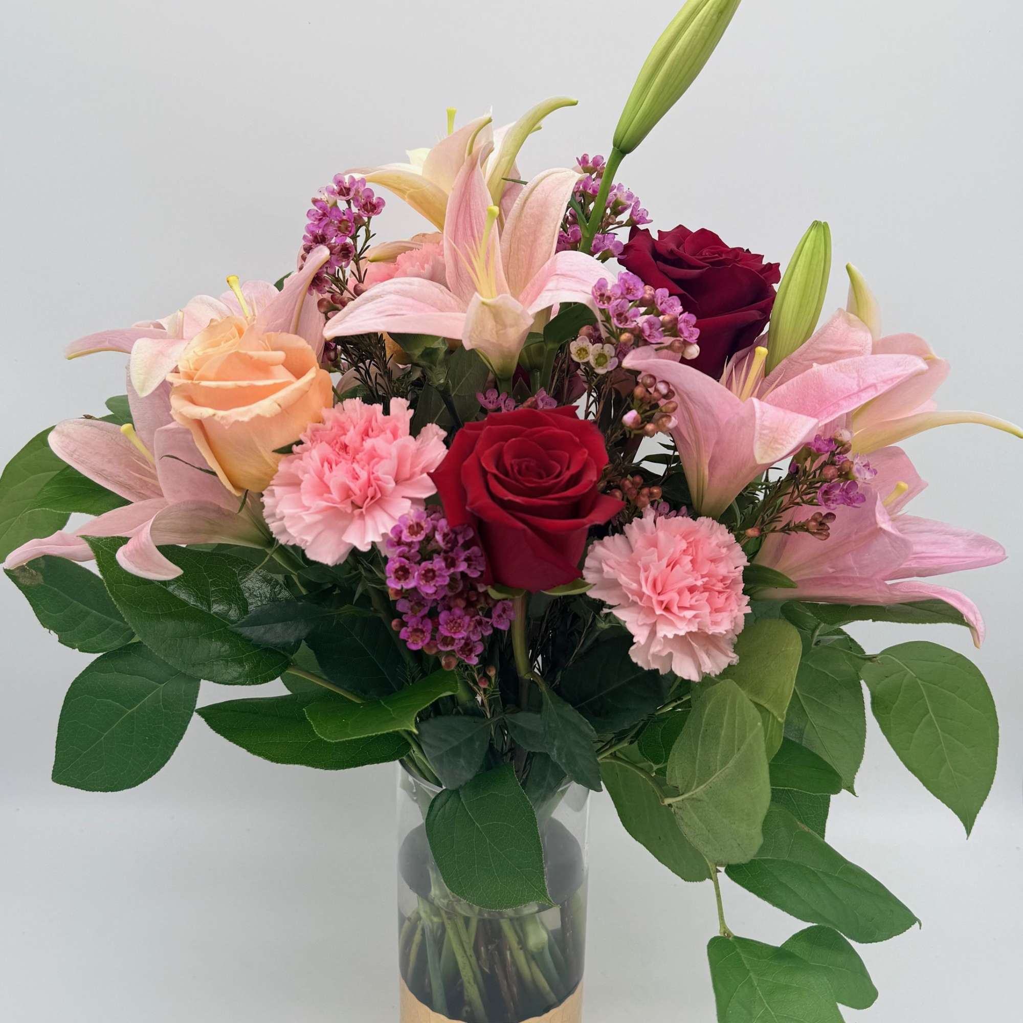 Bouquet of pink lilies, roses, and carnations in a glass vase
