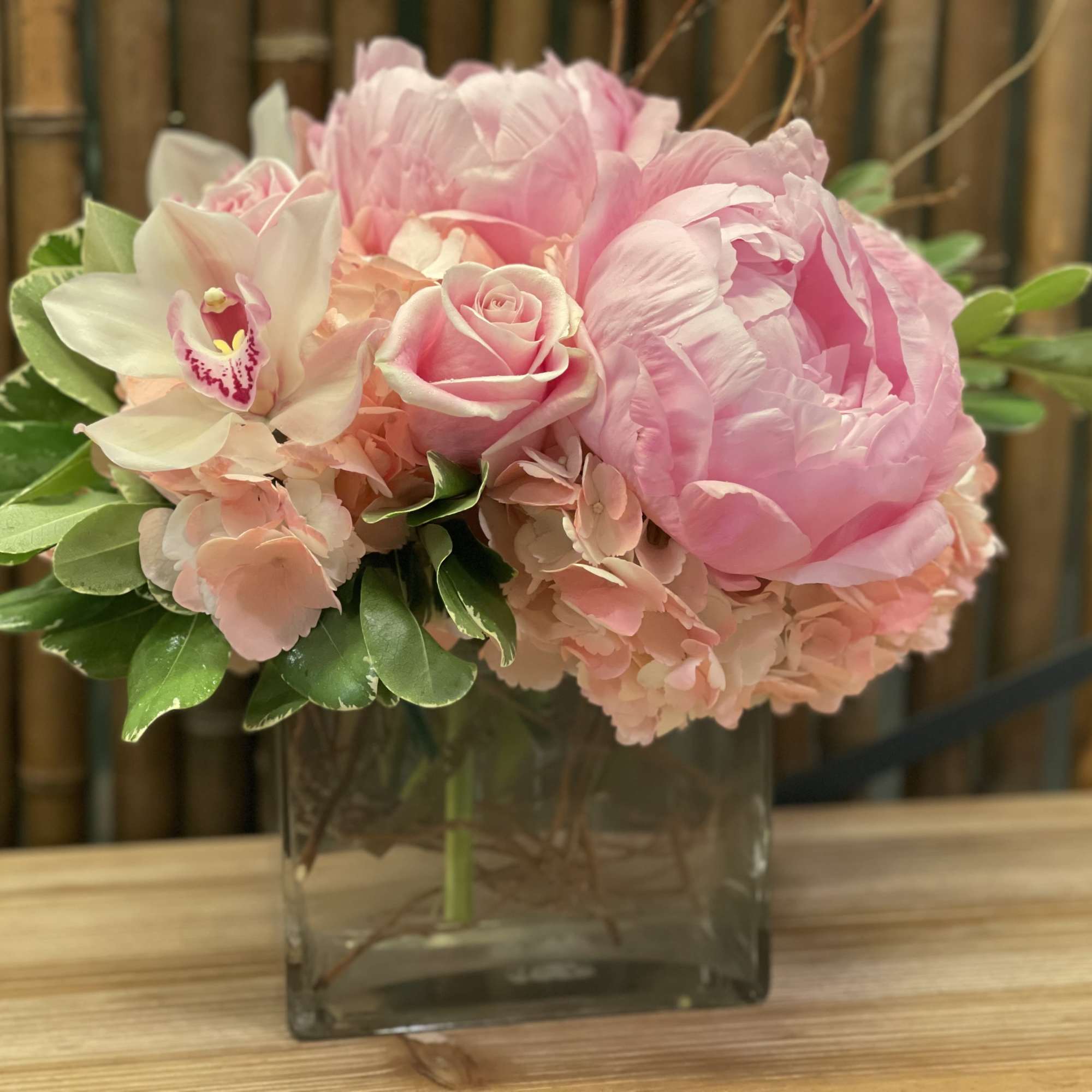 Pink peonies and roses in a square glass vase