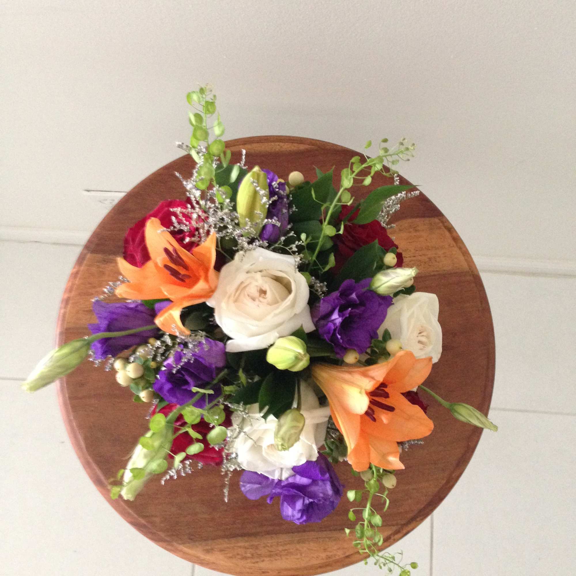 Round bouquet with white roses, orange lilies, and purple flowers