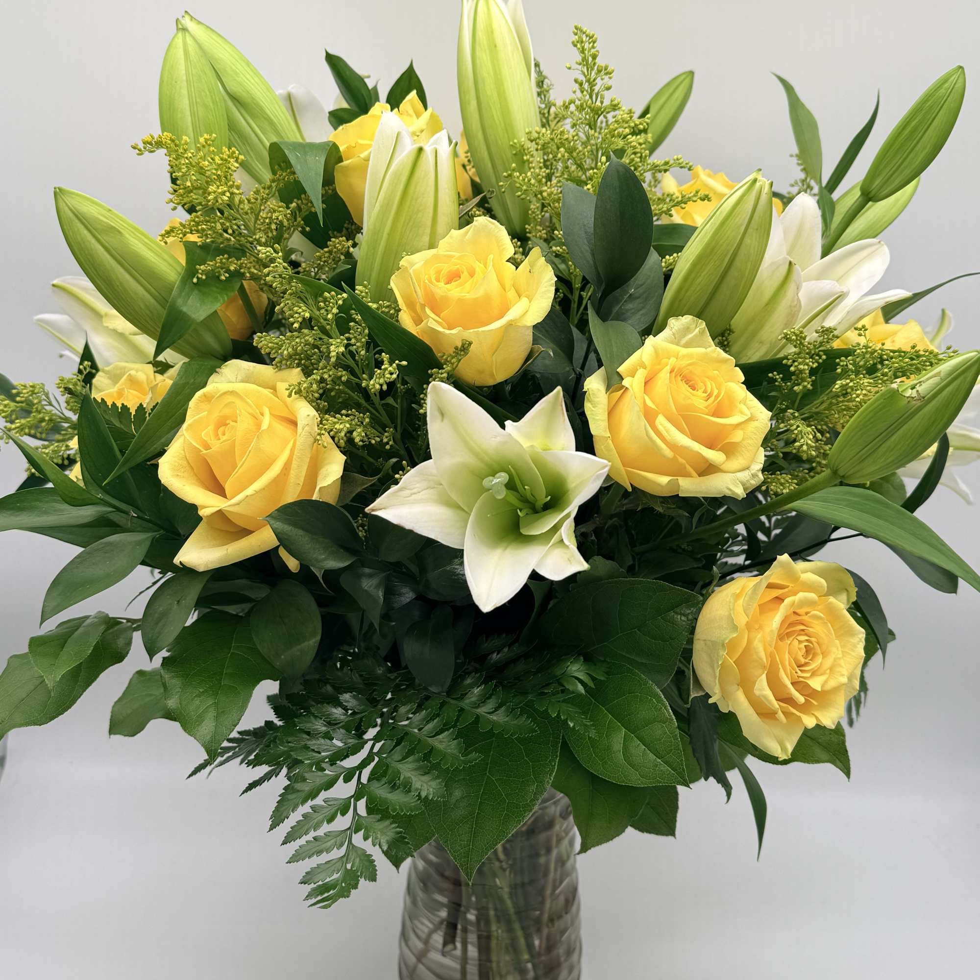 Yellow roses and white lilies in a glass vase