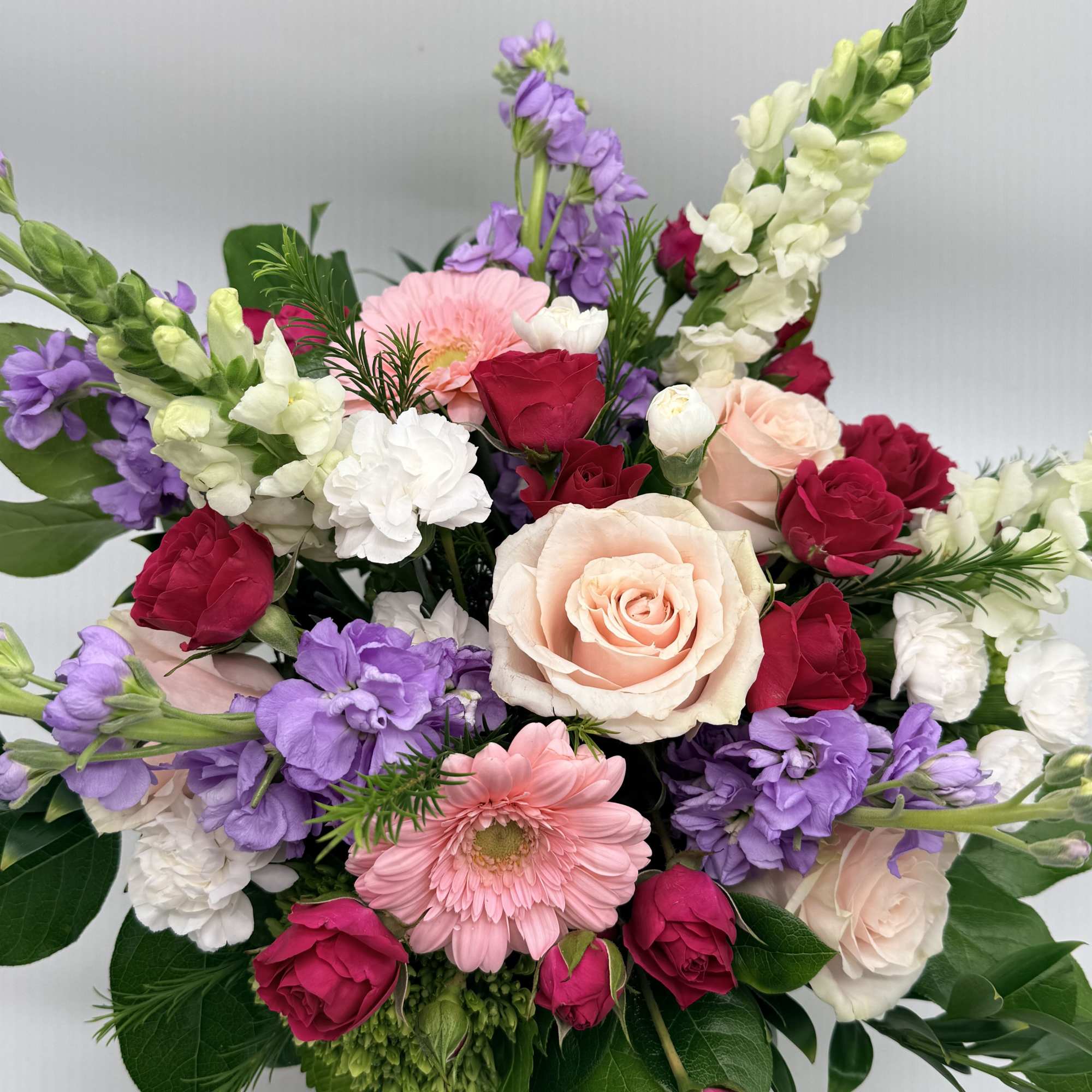 A dreamy mix of blooms designed in a delicate pink vase. 

Shades