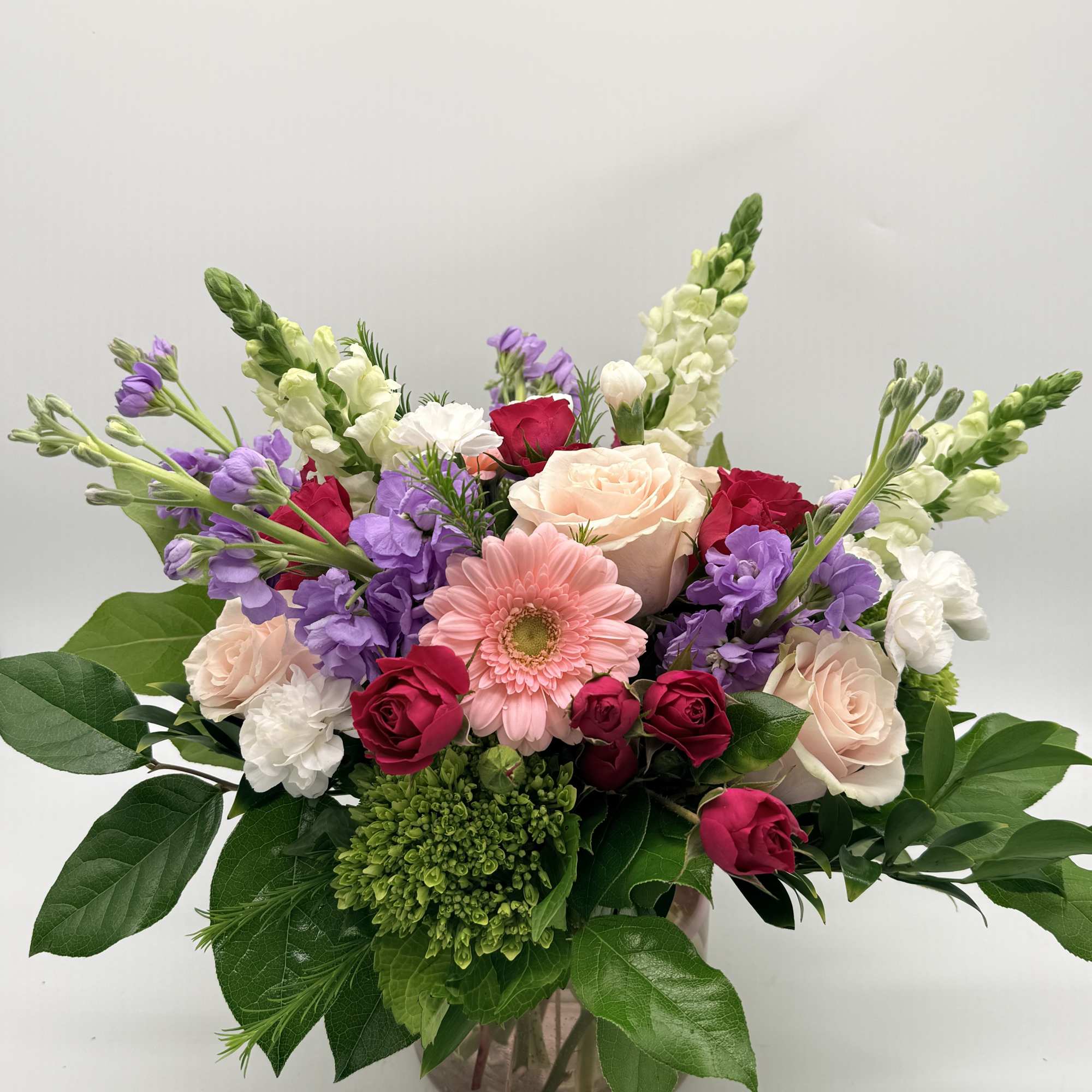 A dreamy mix of blooms designed in a delicate pink vase. 

Shades
