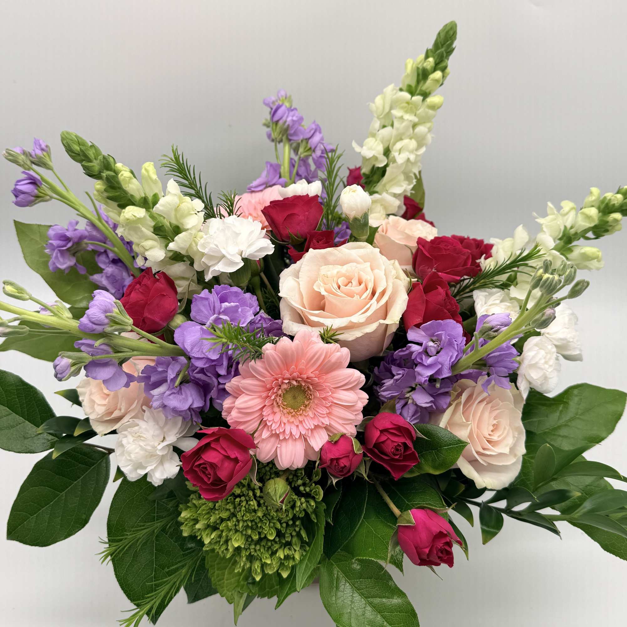 A dreamy mix of blooms designed in a delicate pink vase. 

Shades
