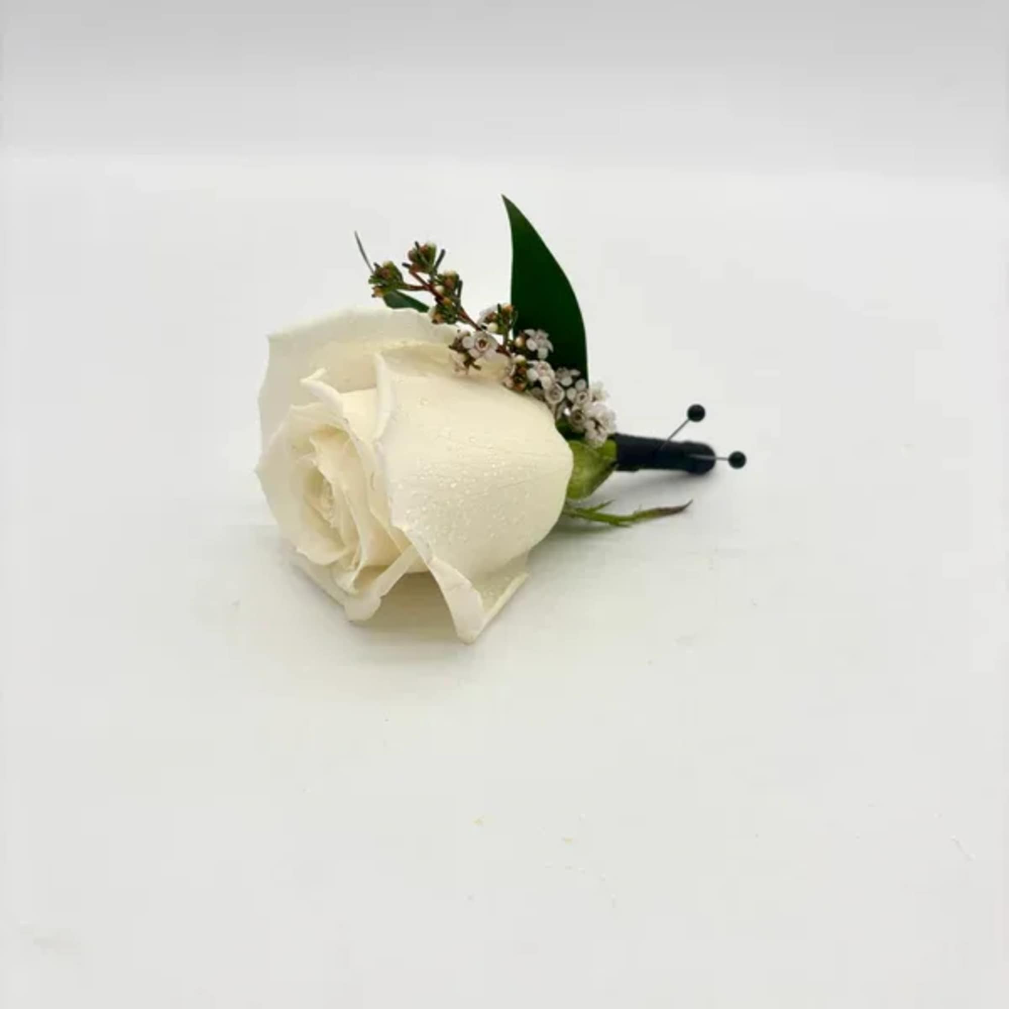 Single white rose boutonniere with tiny white filler flowers and black-wrapped stem