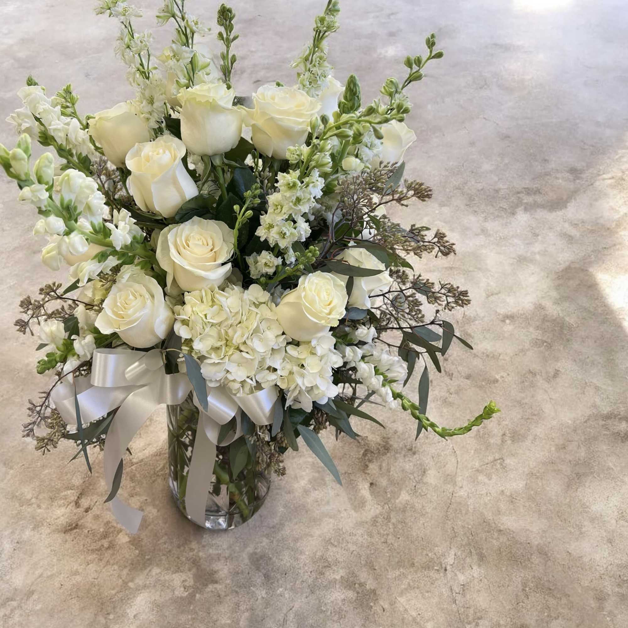 This timeless all-white arrangement brings a sense of serenity and respect, making