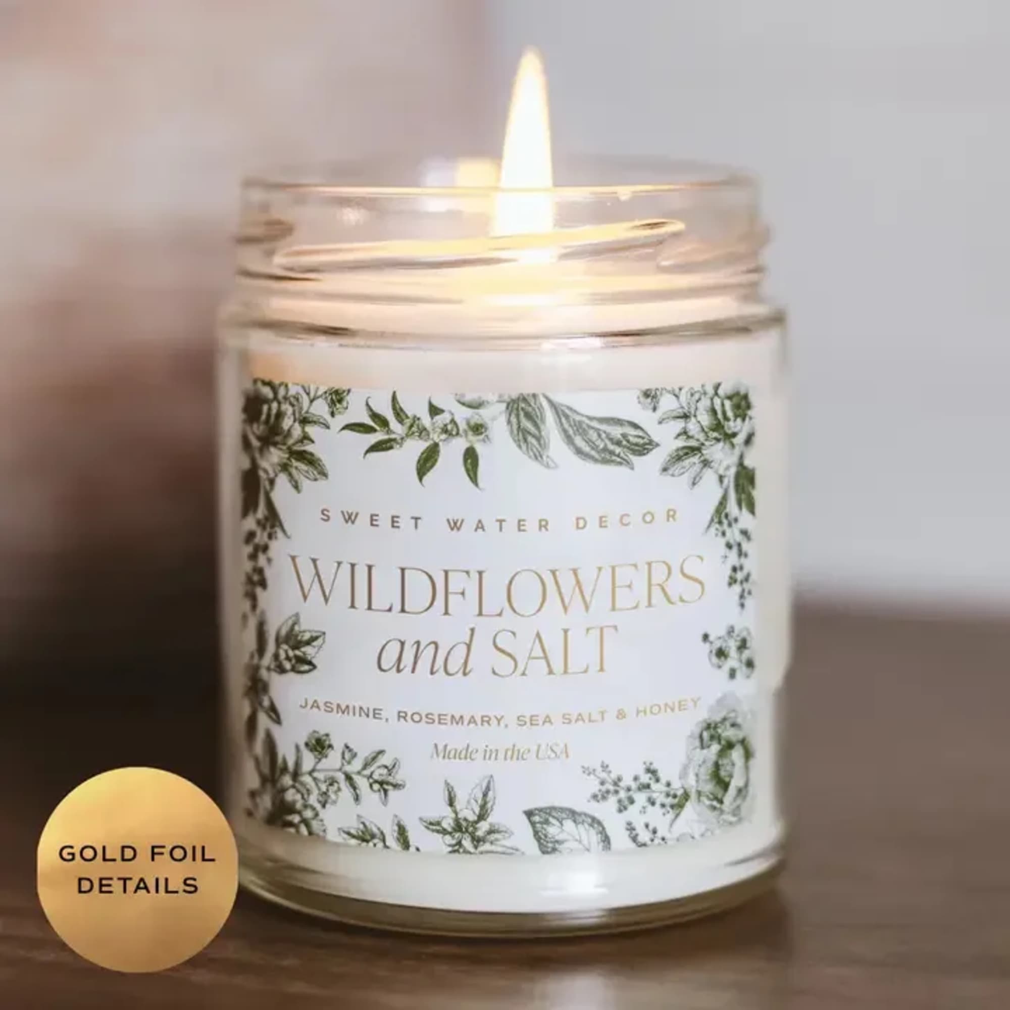 Lit candle in a glass jar with floral label