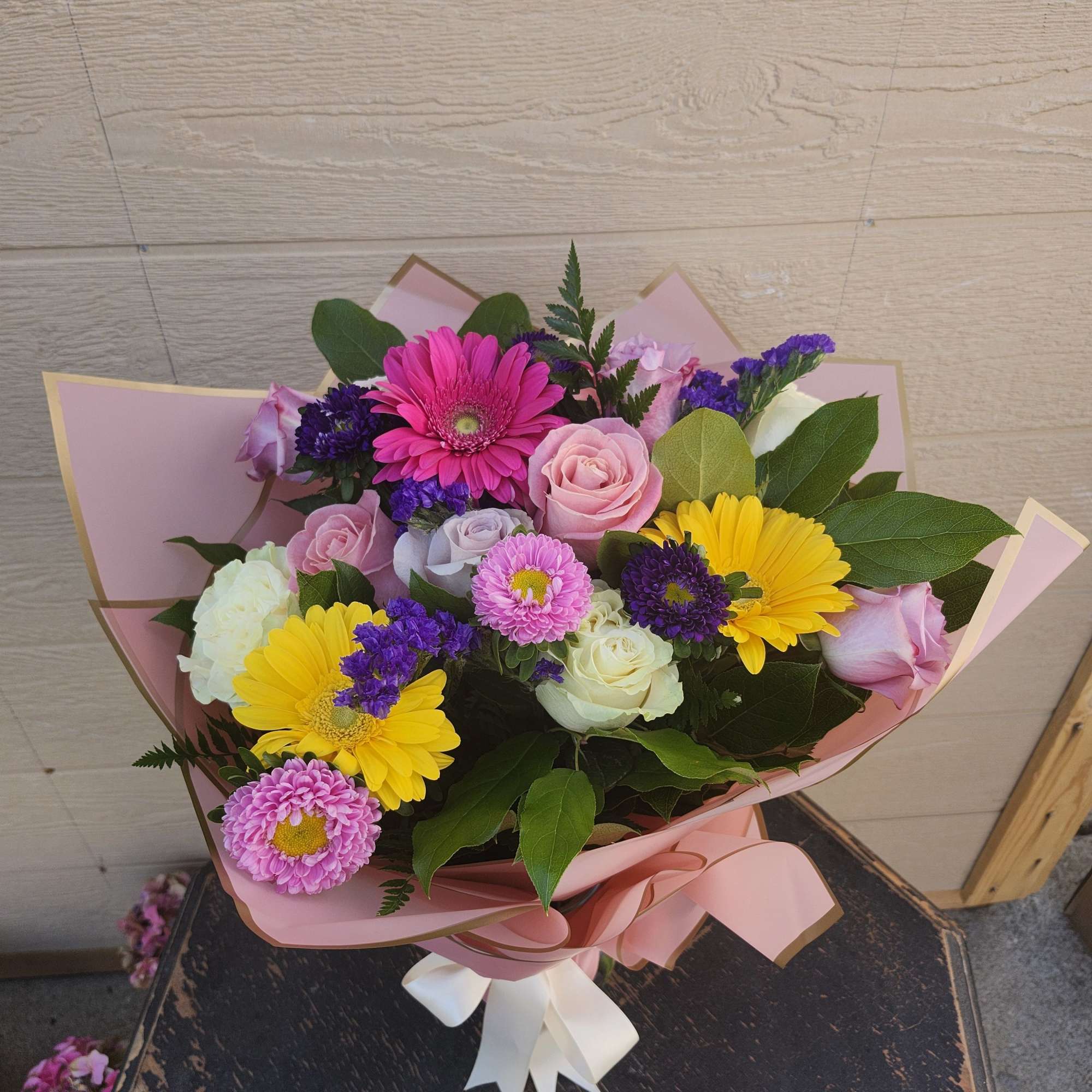 This wrap bouquet shown in large.
2 dozen roses designer's choice. All florals