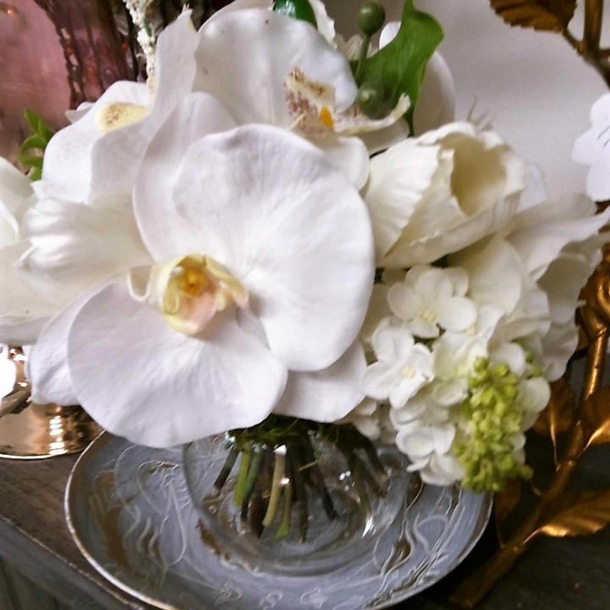 White orchid bouquet in a clear glass vase on a silver tray